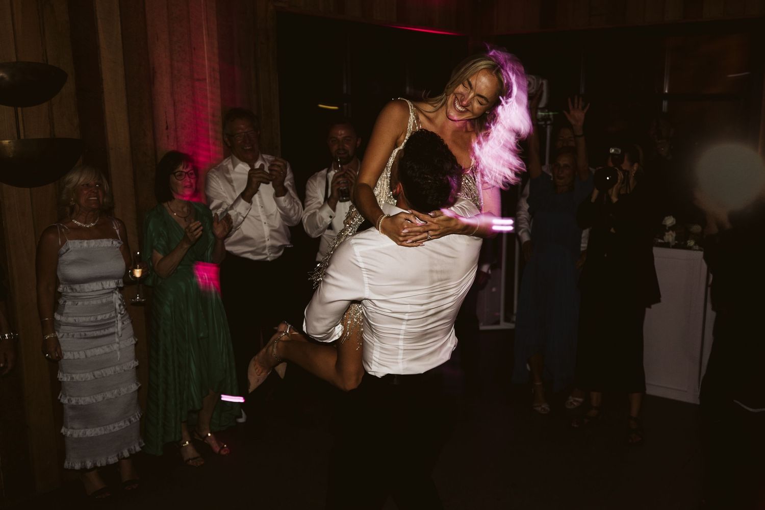 A dynamic dance move captured during a wedding reception with dramatic lighting.