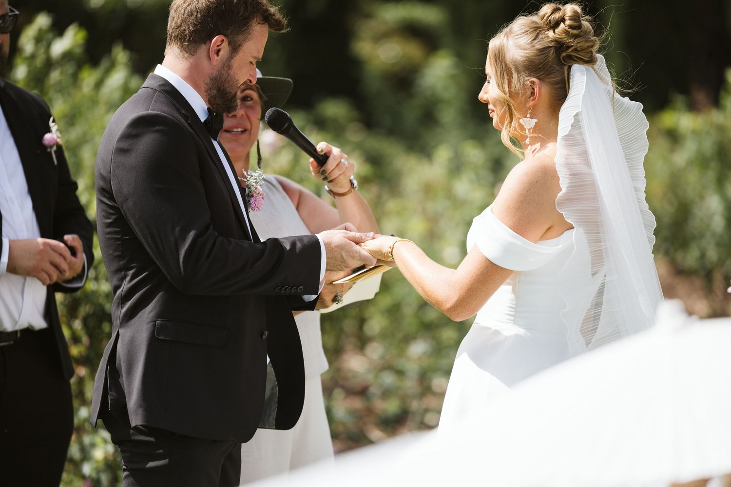 Couple exchanges rings during outdoor garden wedding ceremony.