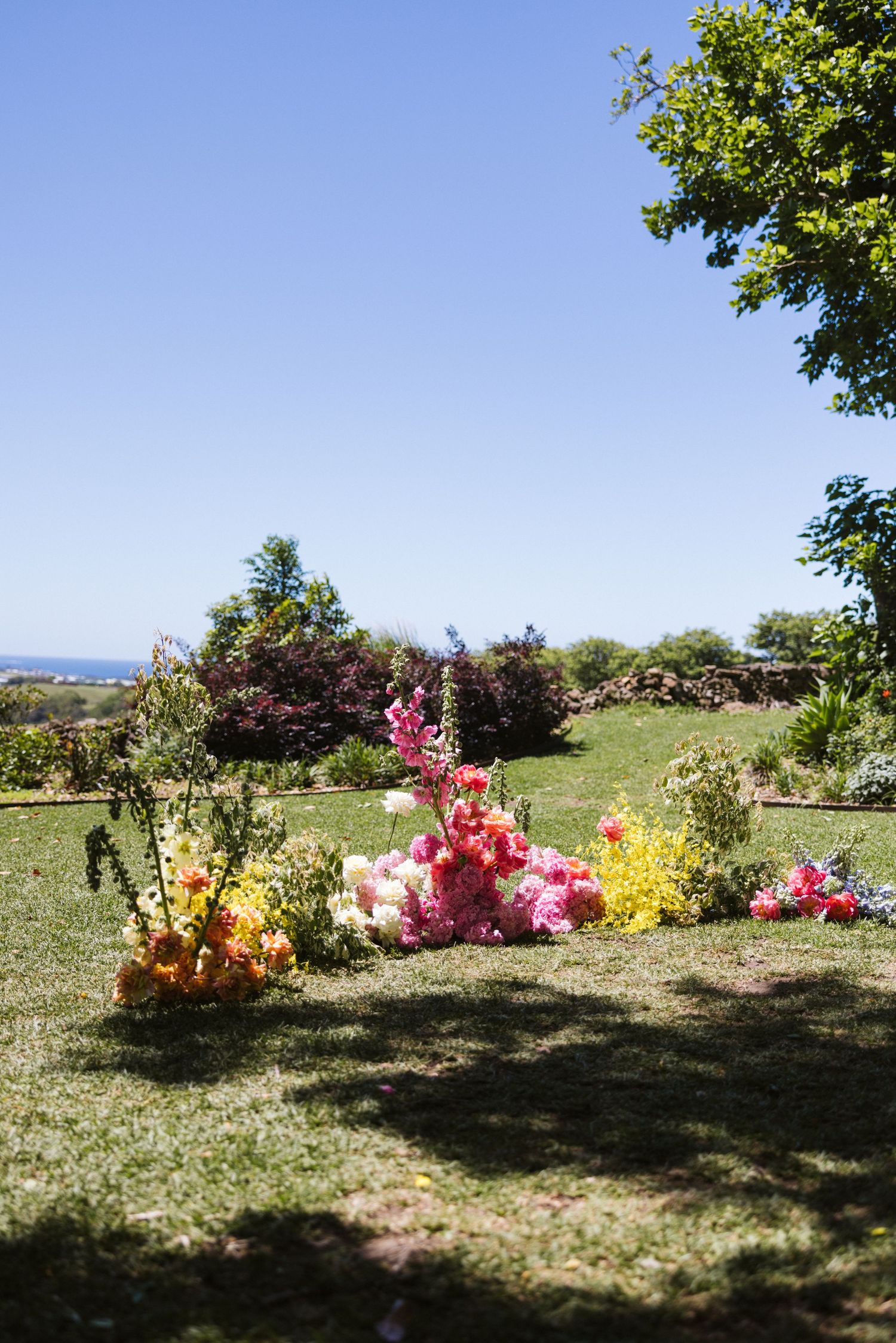 Colorful floral arrangement featuring pink and yellow blooms against garden backdrop.