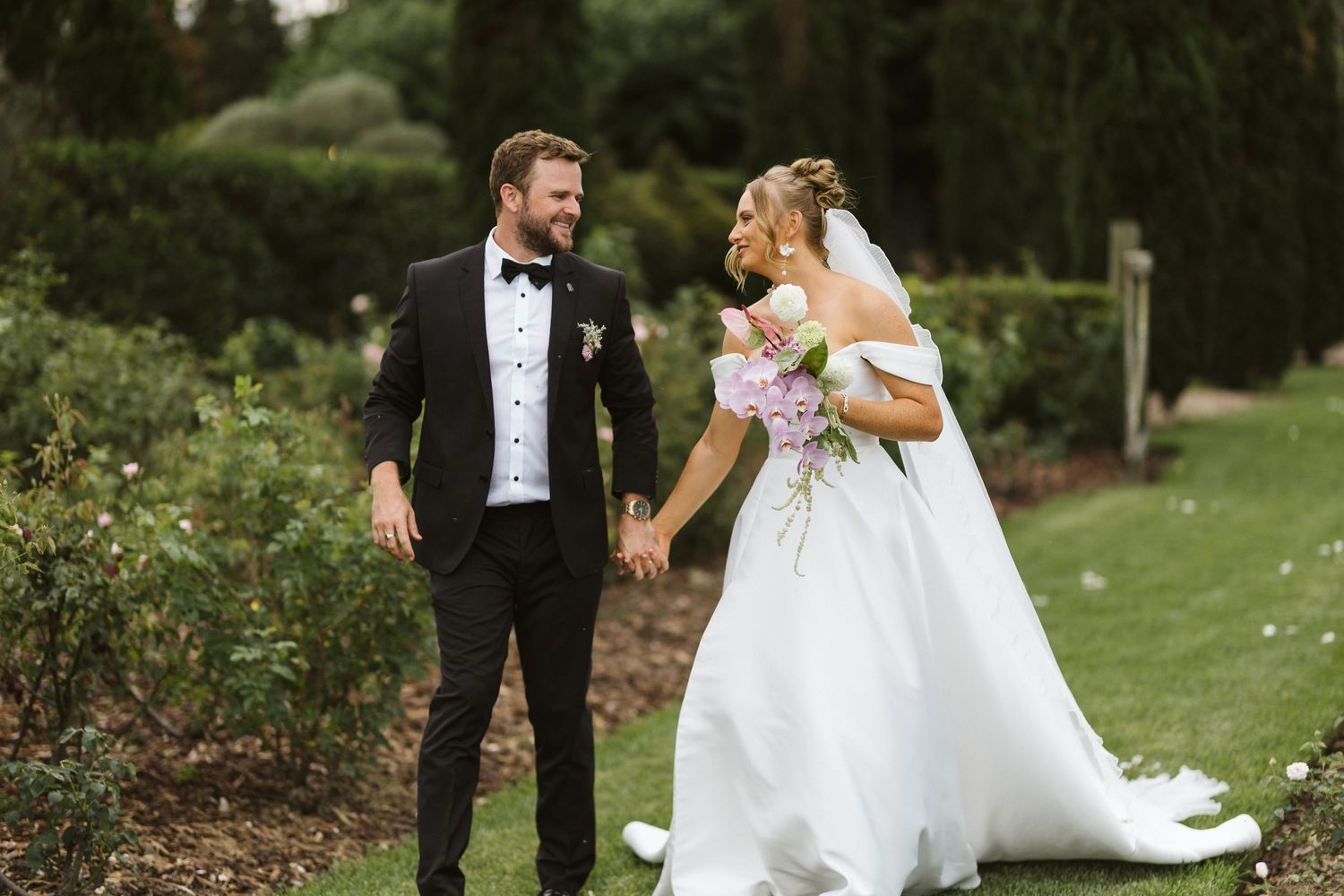 Wedding couple sharing joyful moment in lush garden setting.