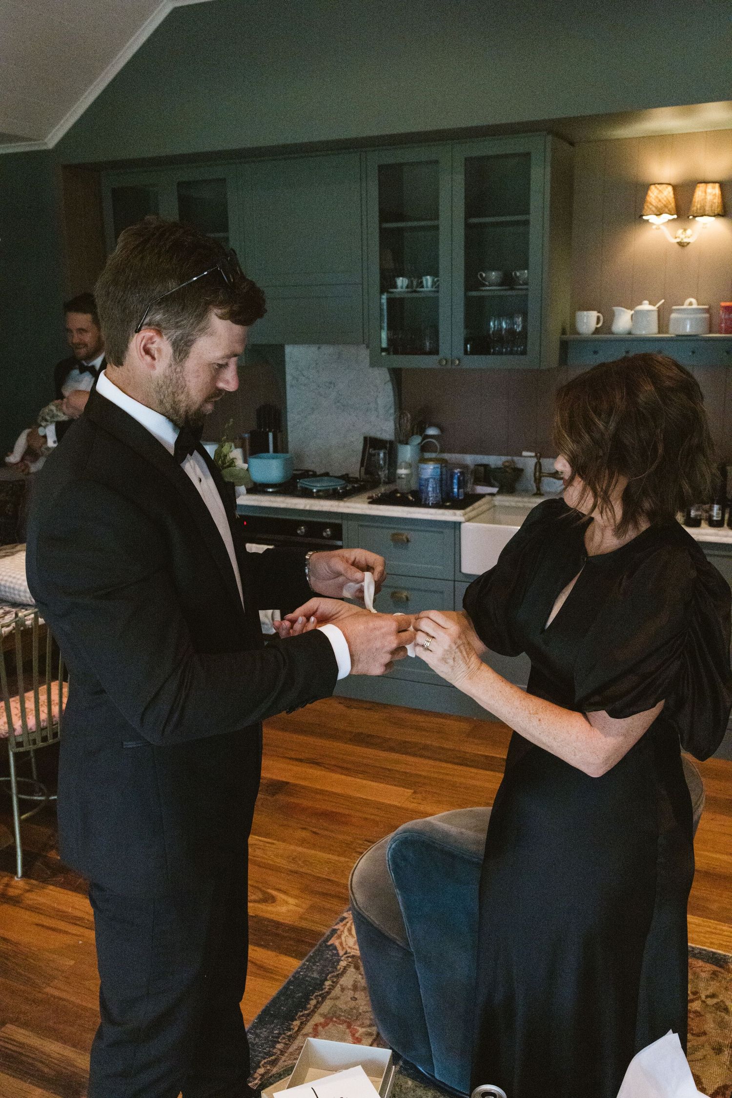 Wedding preparation moment with formal attire in kitchen setting.