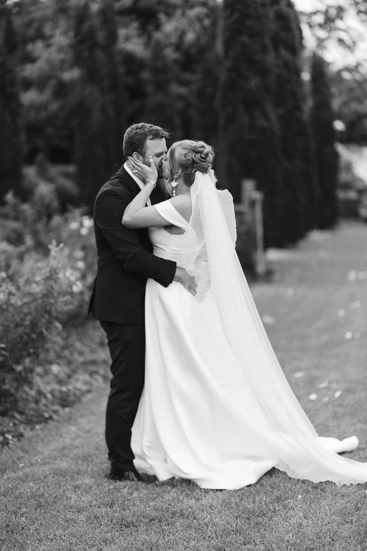 Black and white portrait of a tender wedding embrace in a garden setting.