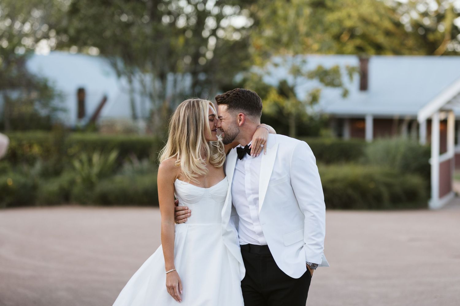 A tender moment between newlyweds against a rustic outdoor backdrop.