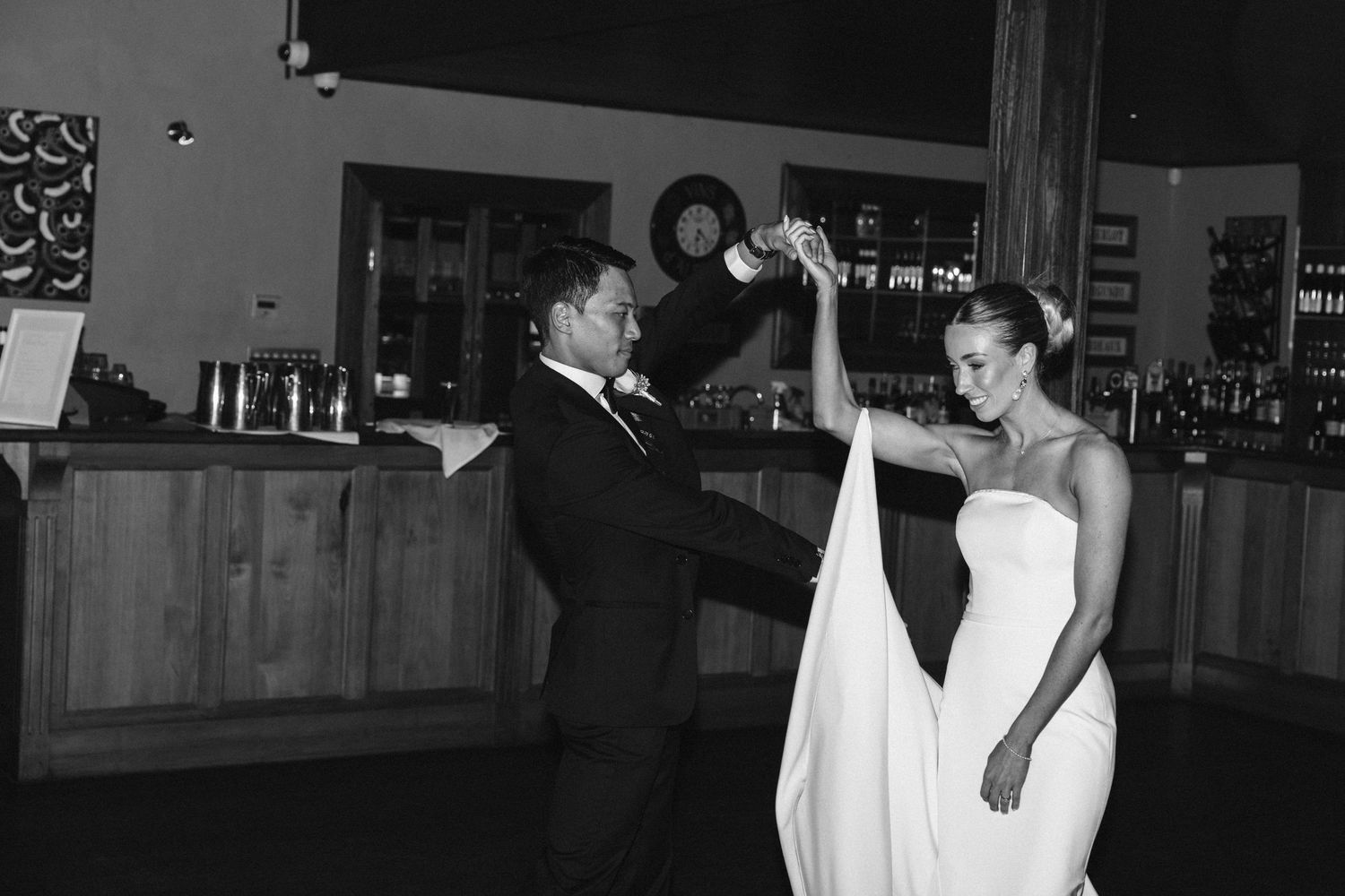 A couple performs an elegant dance move during their wedding reception in a rustic venue.