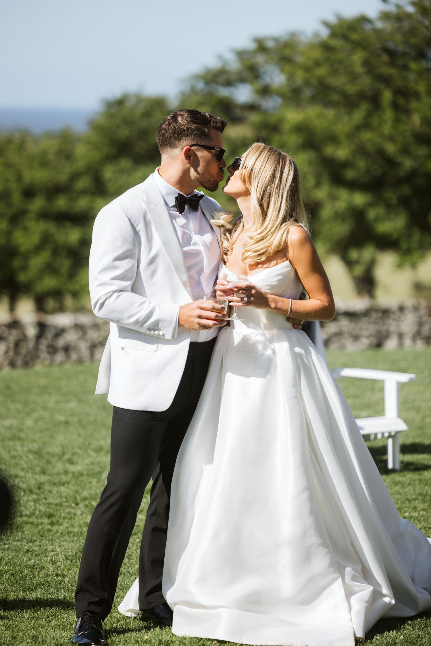 Romantic wedding moment captured outdoors with couple in white formal attire sharing an intimate moment.