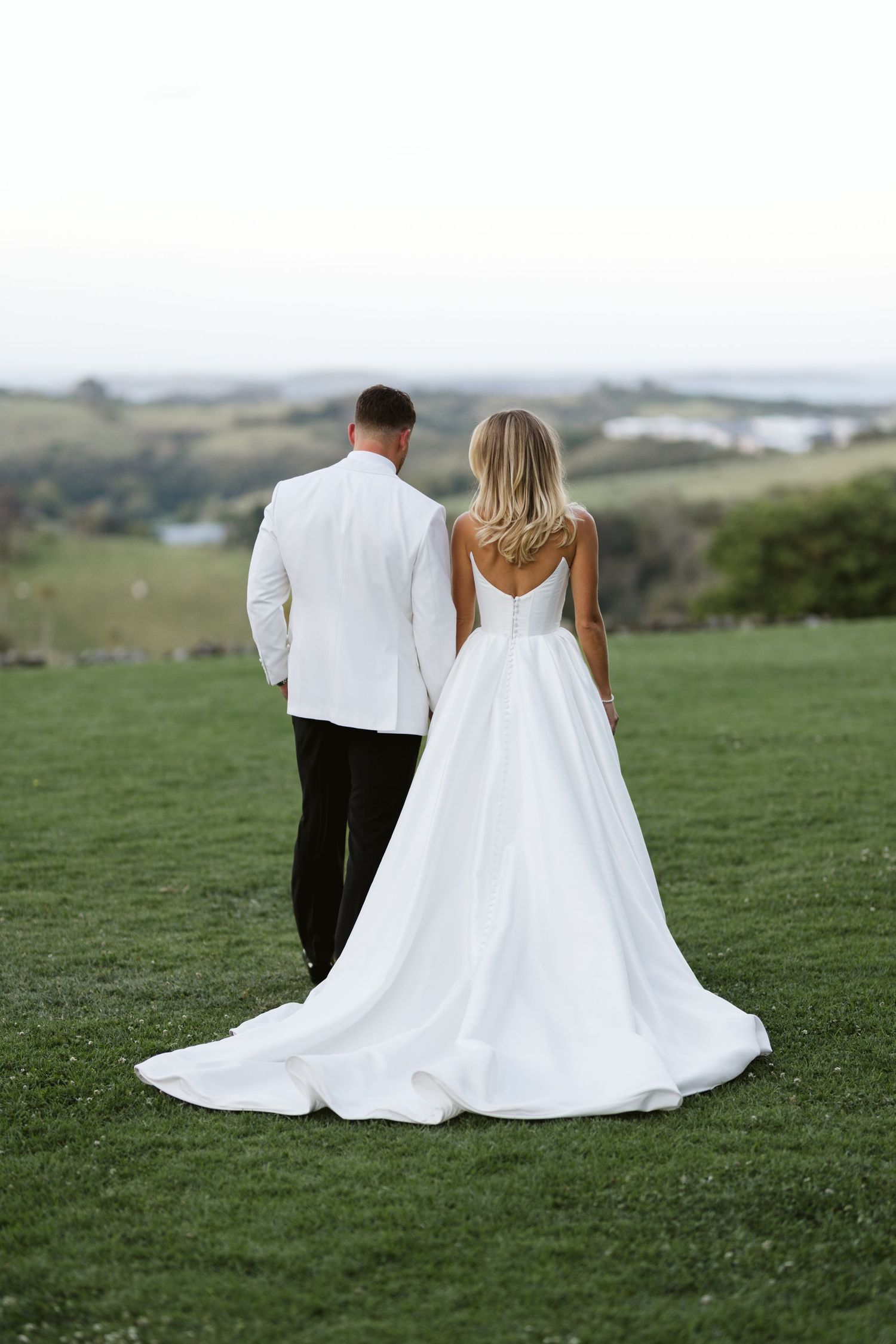 Bride and groom in formal attire overlooking scenic landscape view.