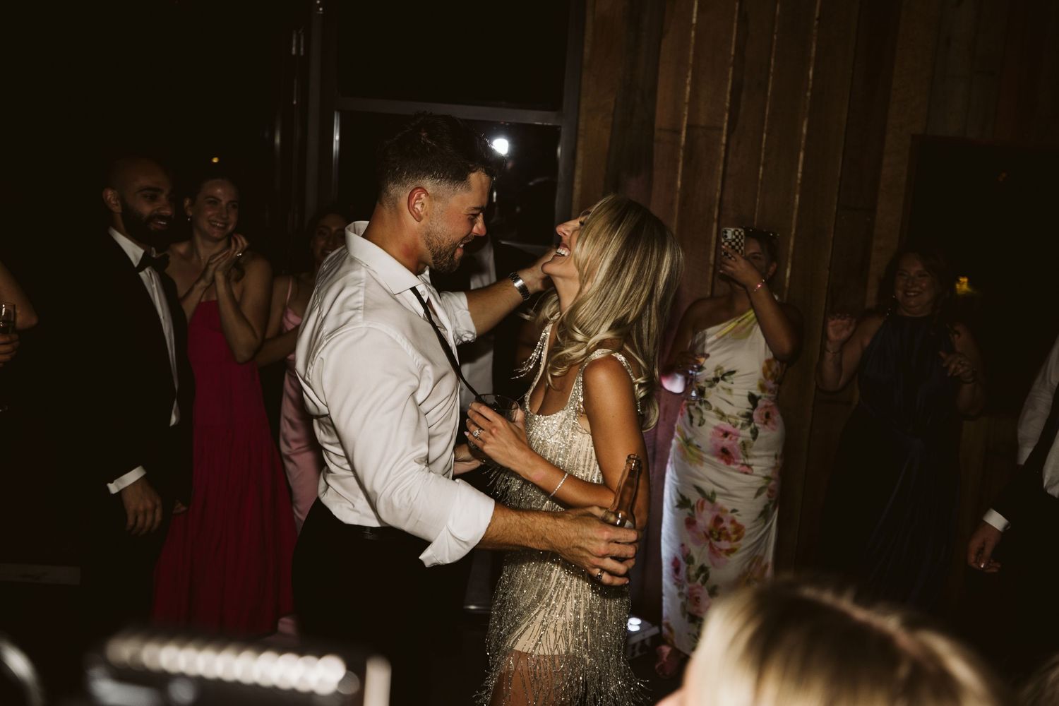 A couple dancing together at their wedding reception in a dimly lit rustic venue.