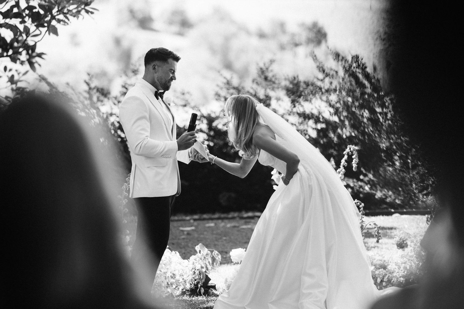 A joyful moment captured during wedding vows in a black and white outdoor ceremony photo.