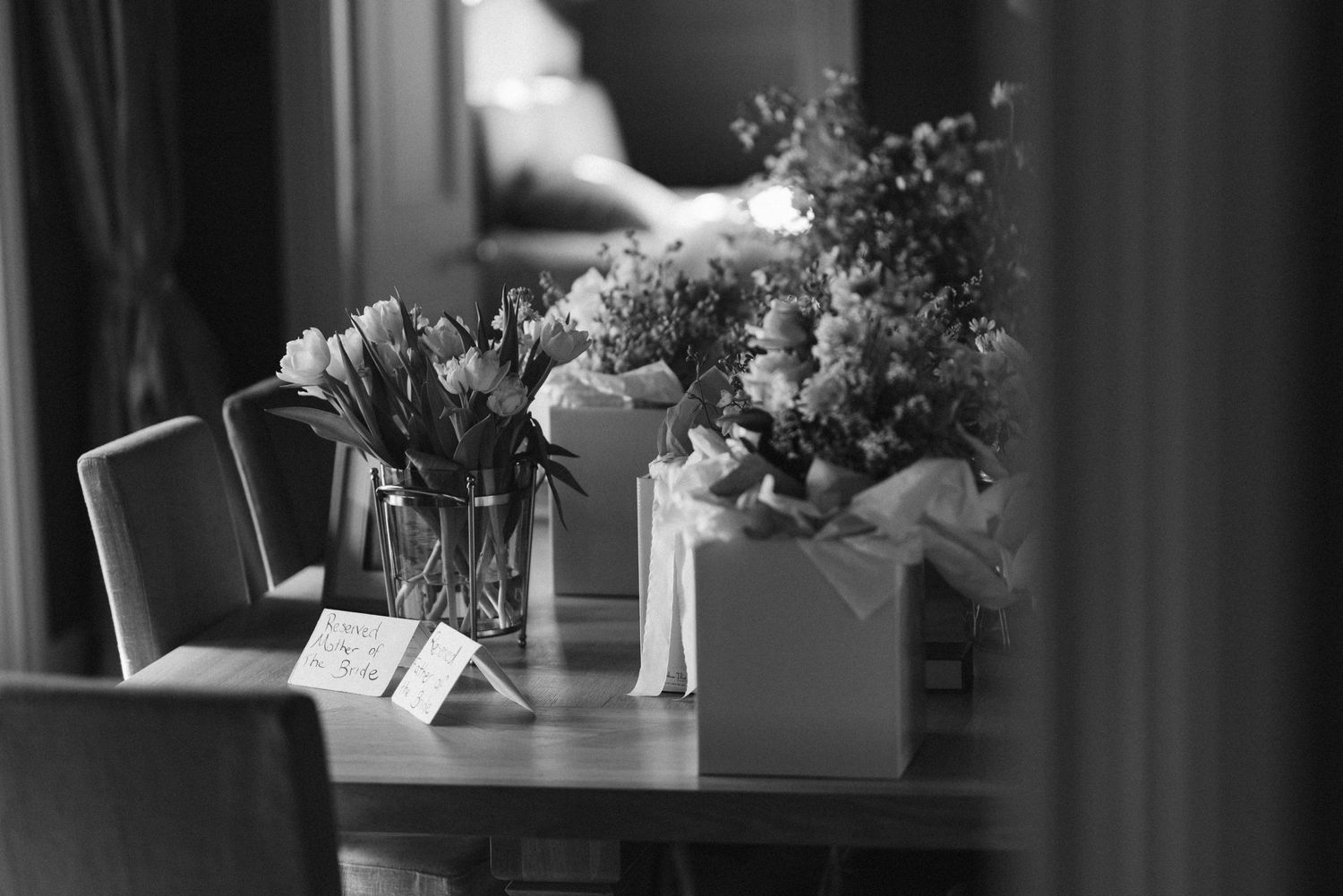 Black and white photo of flower arrangements on dining table.