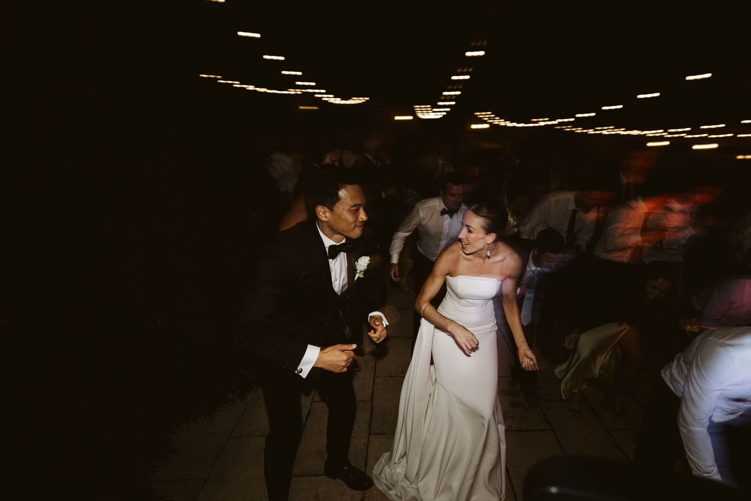 A couple dancing together at their dimly lit wedding reception.