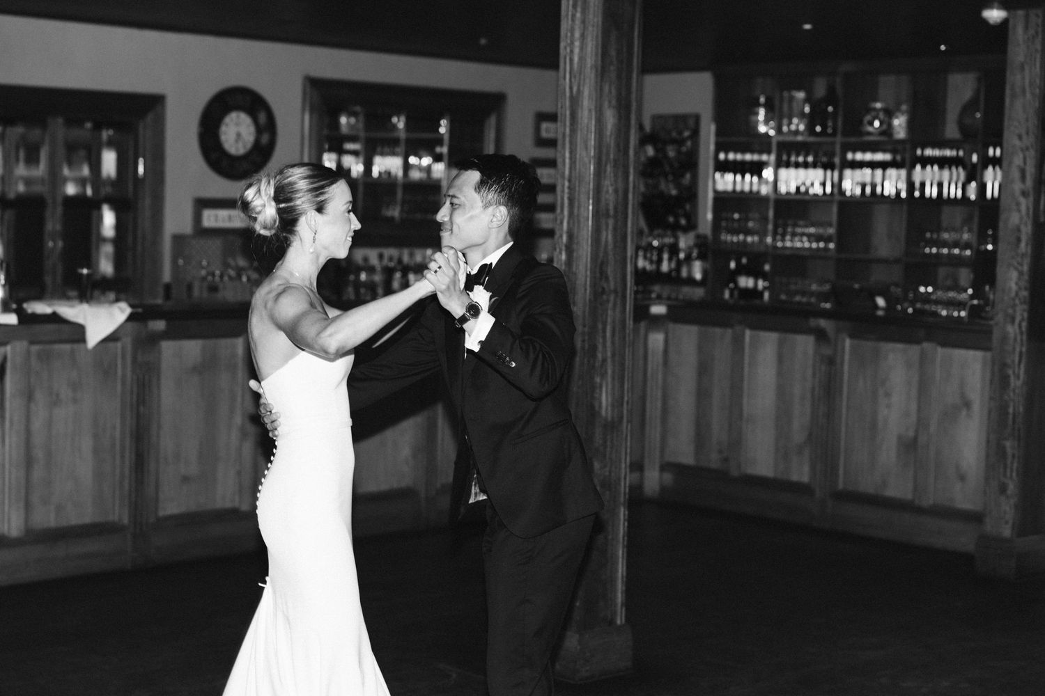 A couple dances energetically in black and white at their wedding reception.