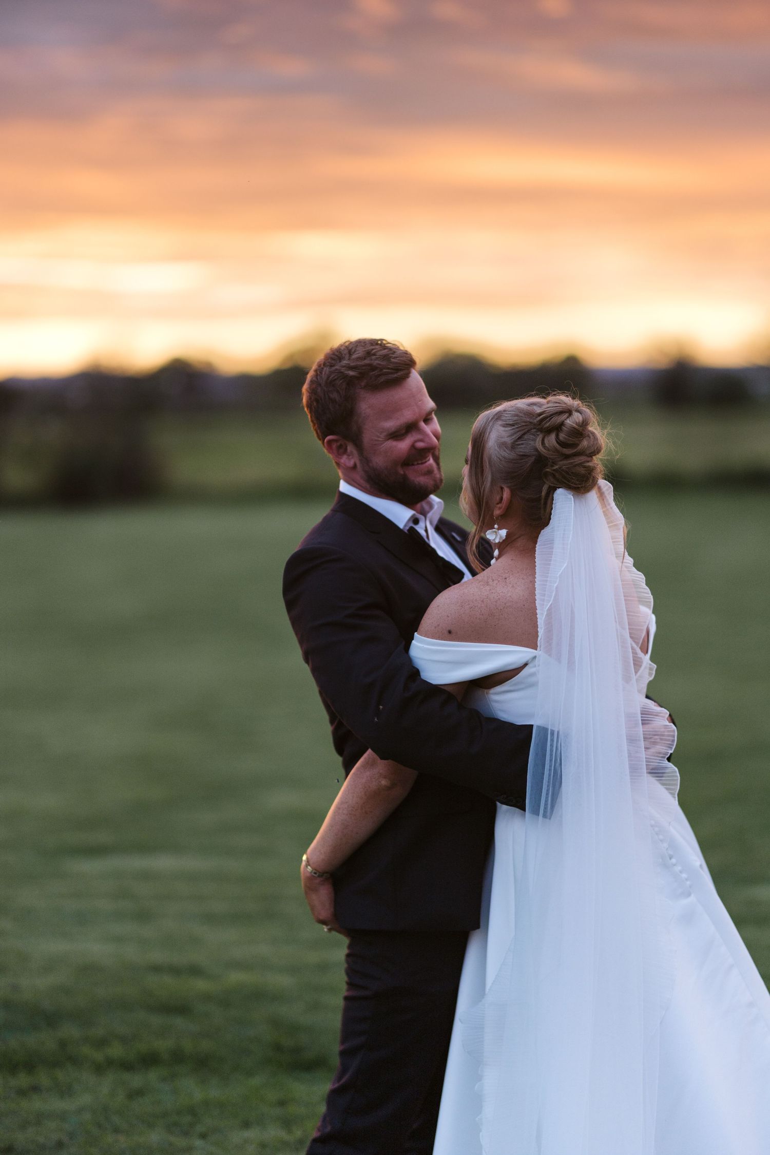 Newlyweds share an intimate moment against a stunning sunset backdrop.
