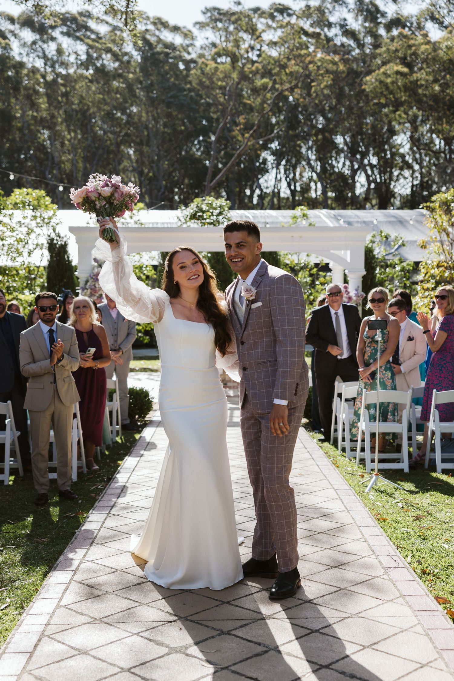 Wedding ceremony on an outdoor patio with guests watching as newlyweds share their first dance.