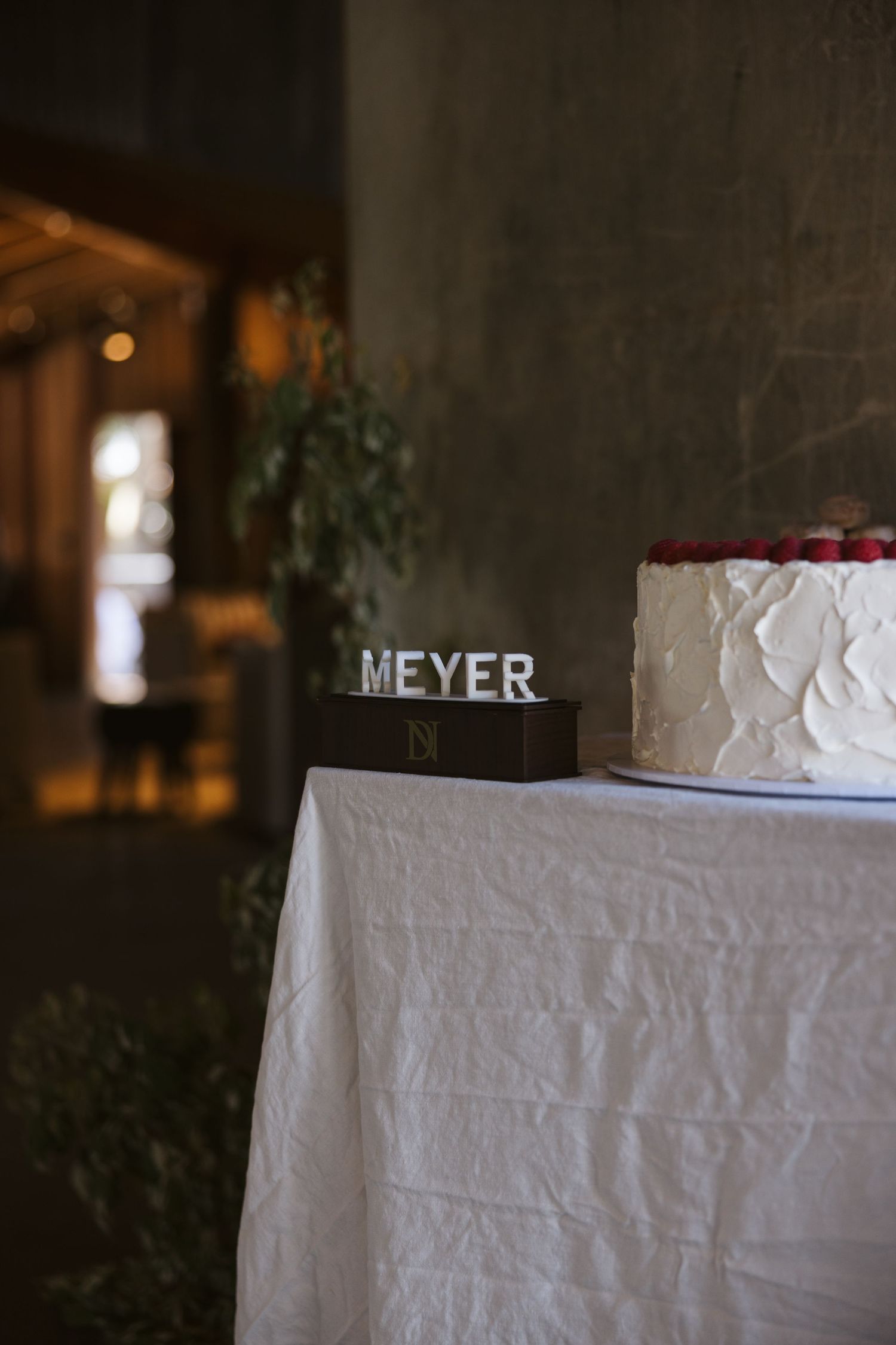 Wedding cake detail showing custom Meyer name plate against rustic backdrop.