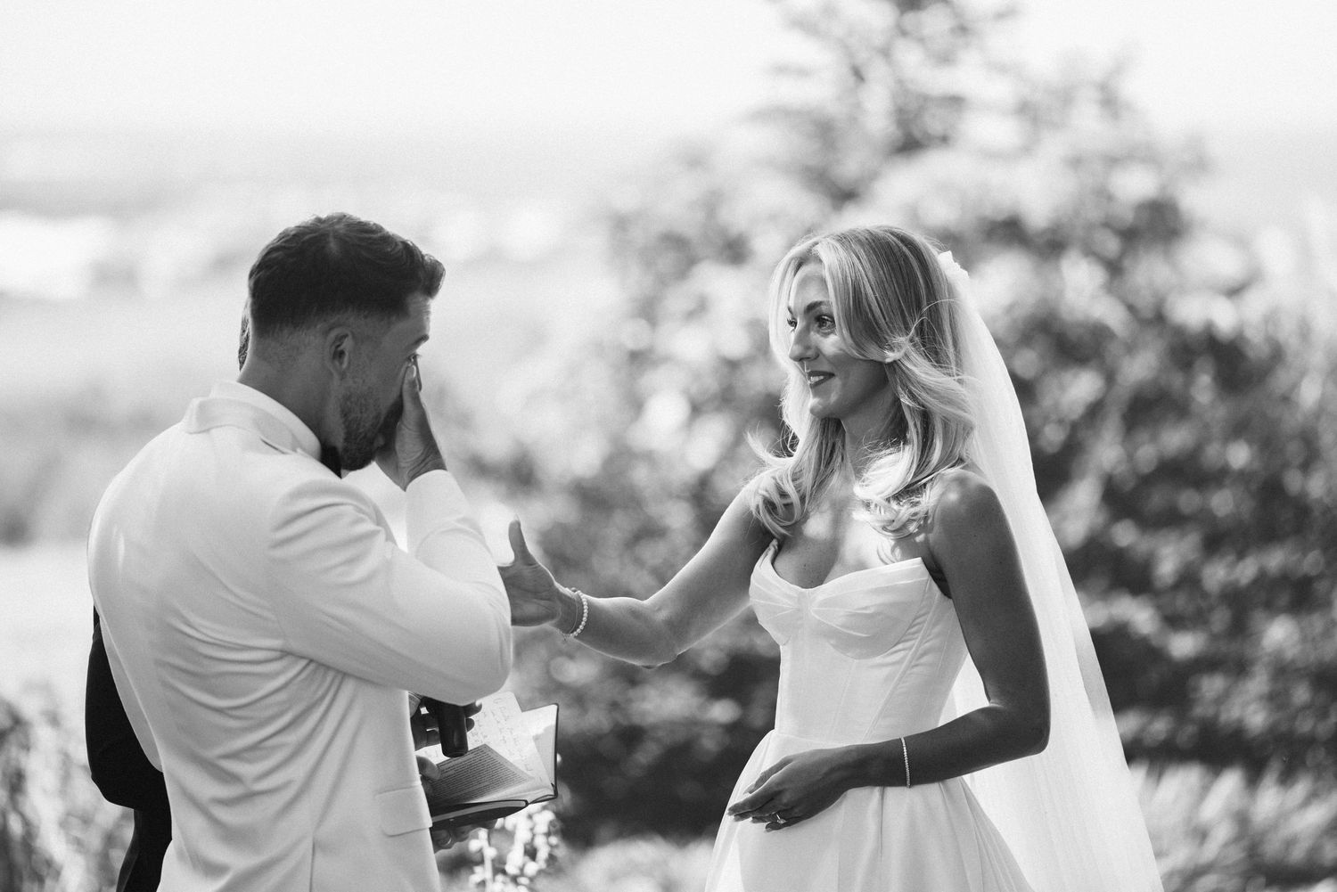 Black and white capture of a heartfelt exchange during outdoor wedding vows.