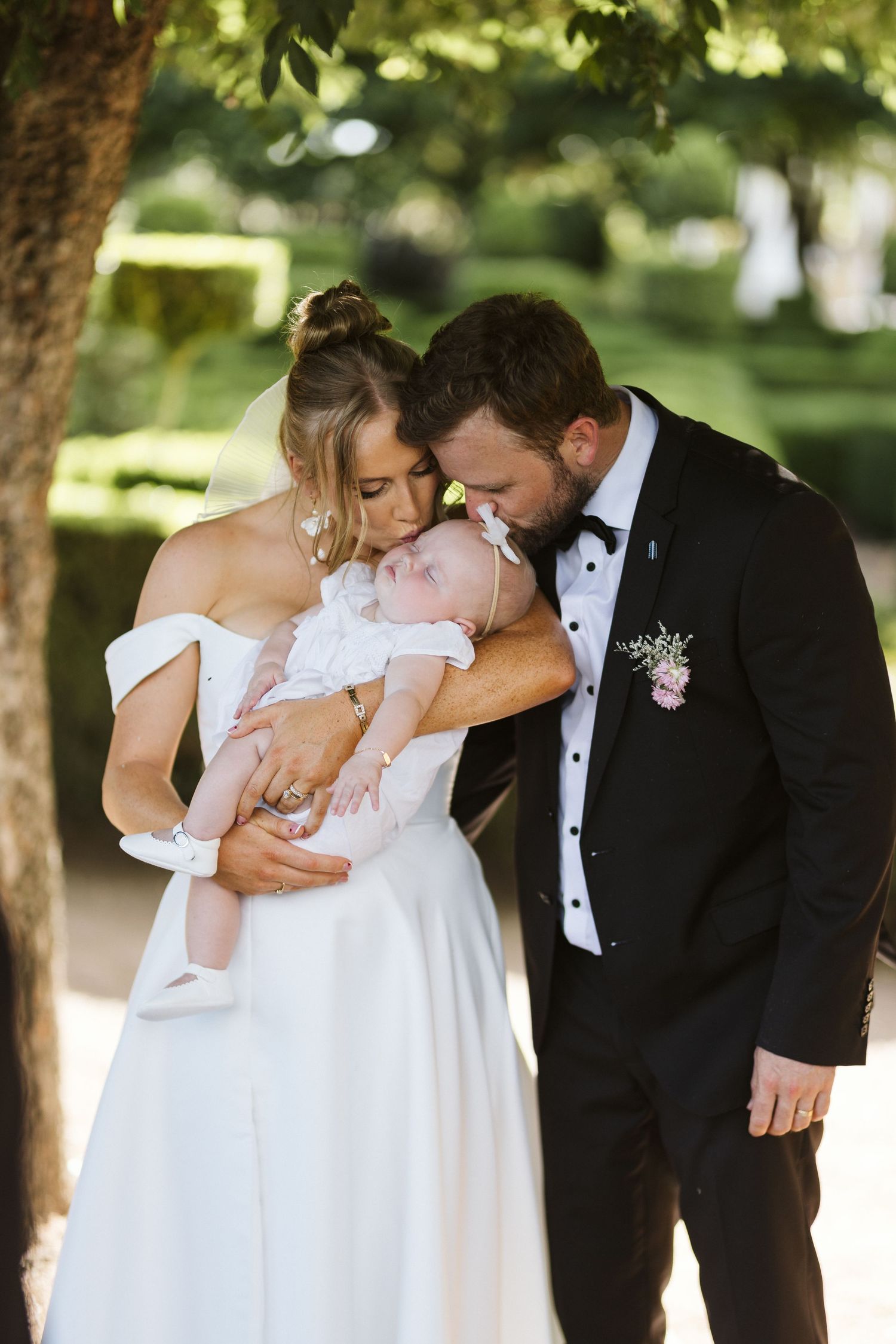 Tender family moment captured during outdoor wedding celebration.
