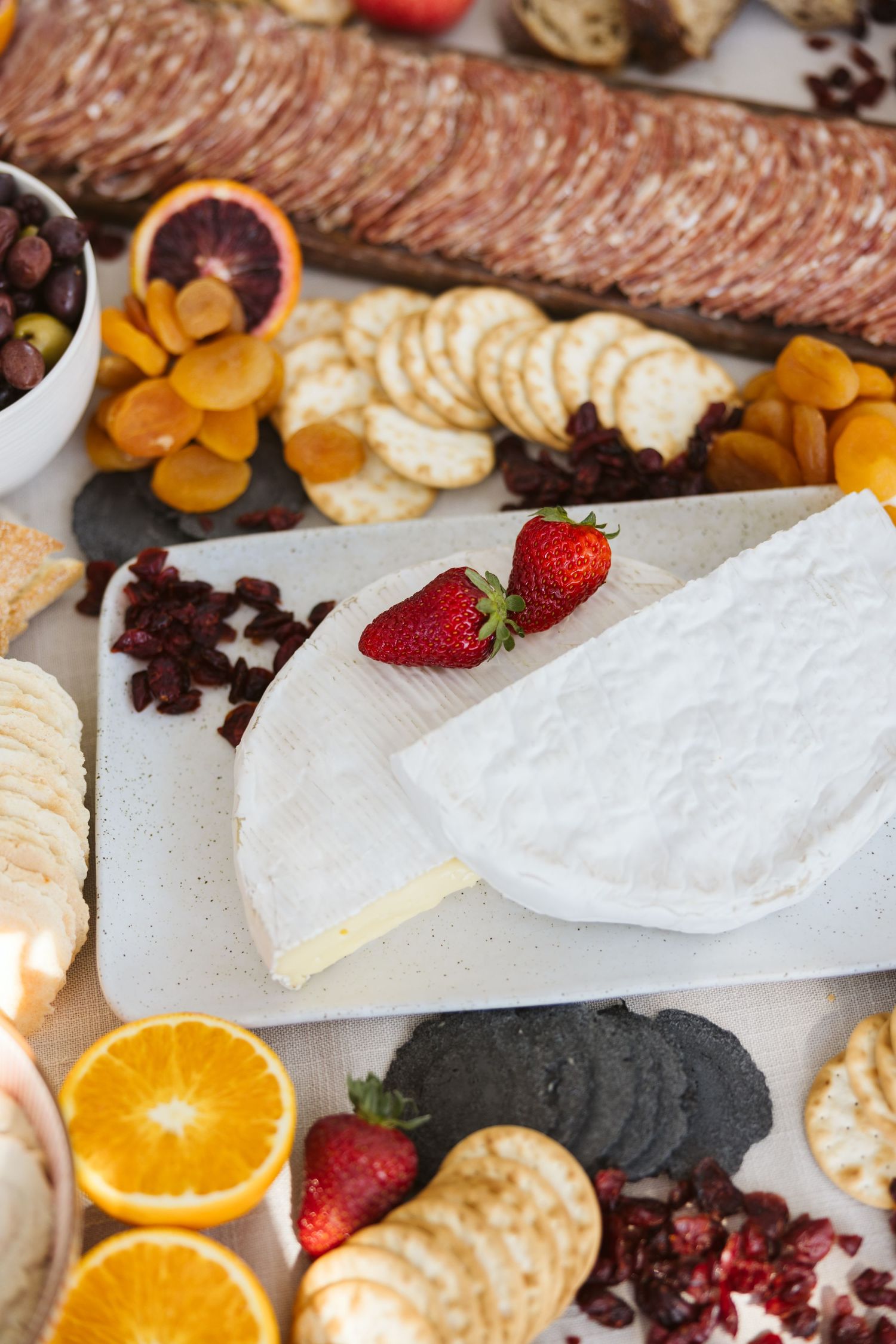 A luxurious cheese and charcuterie board with fresh fruit, crackers, and brie cheese.