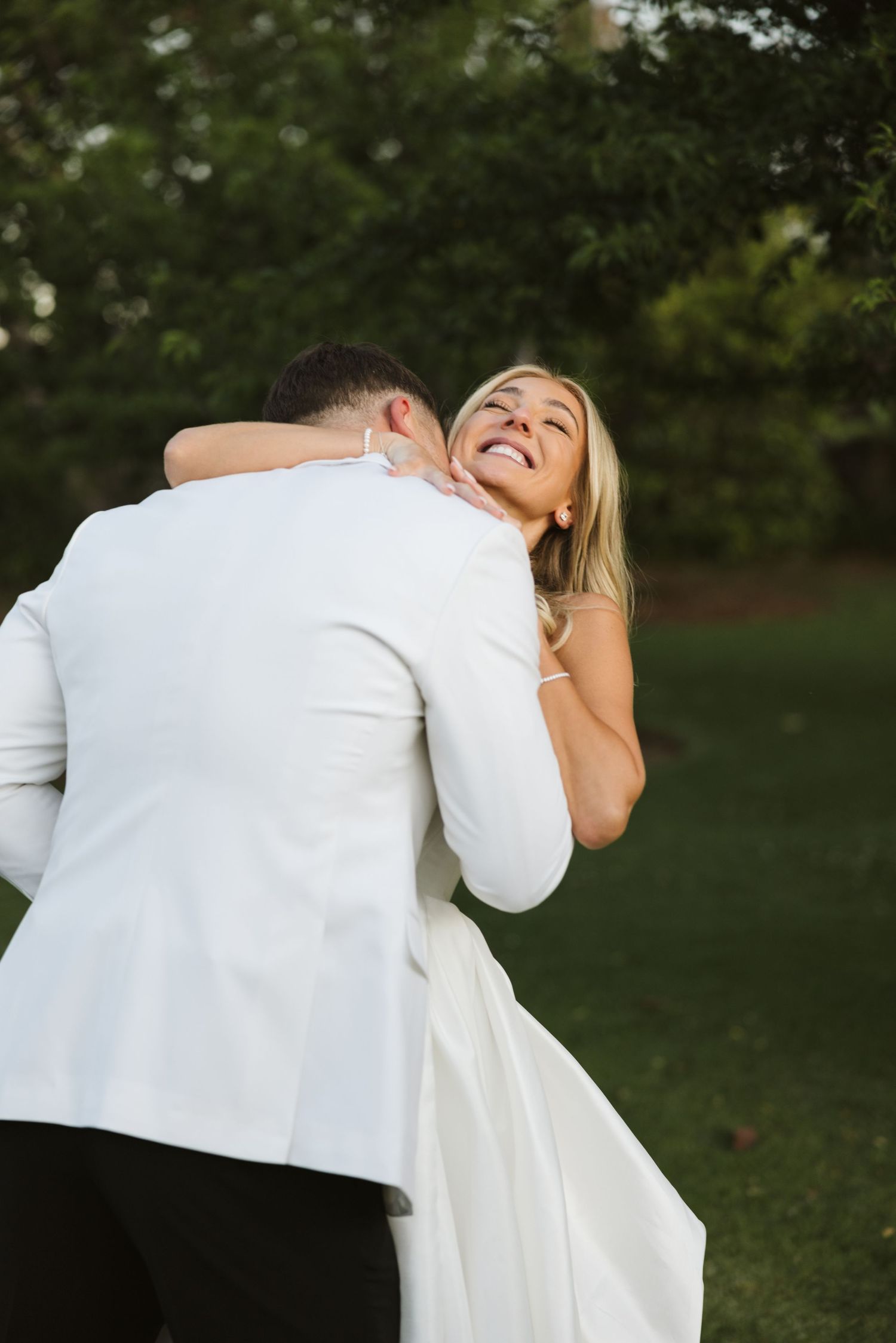 Couple in wedding attire sharing a tender embrace and laugh on their special day.