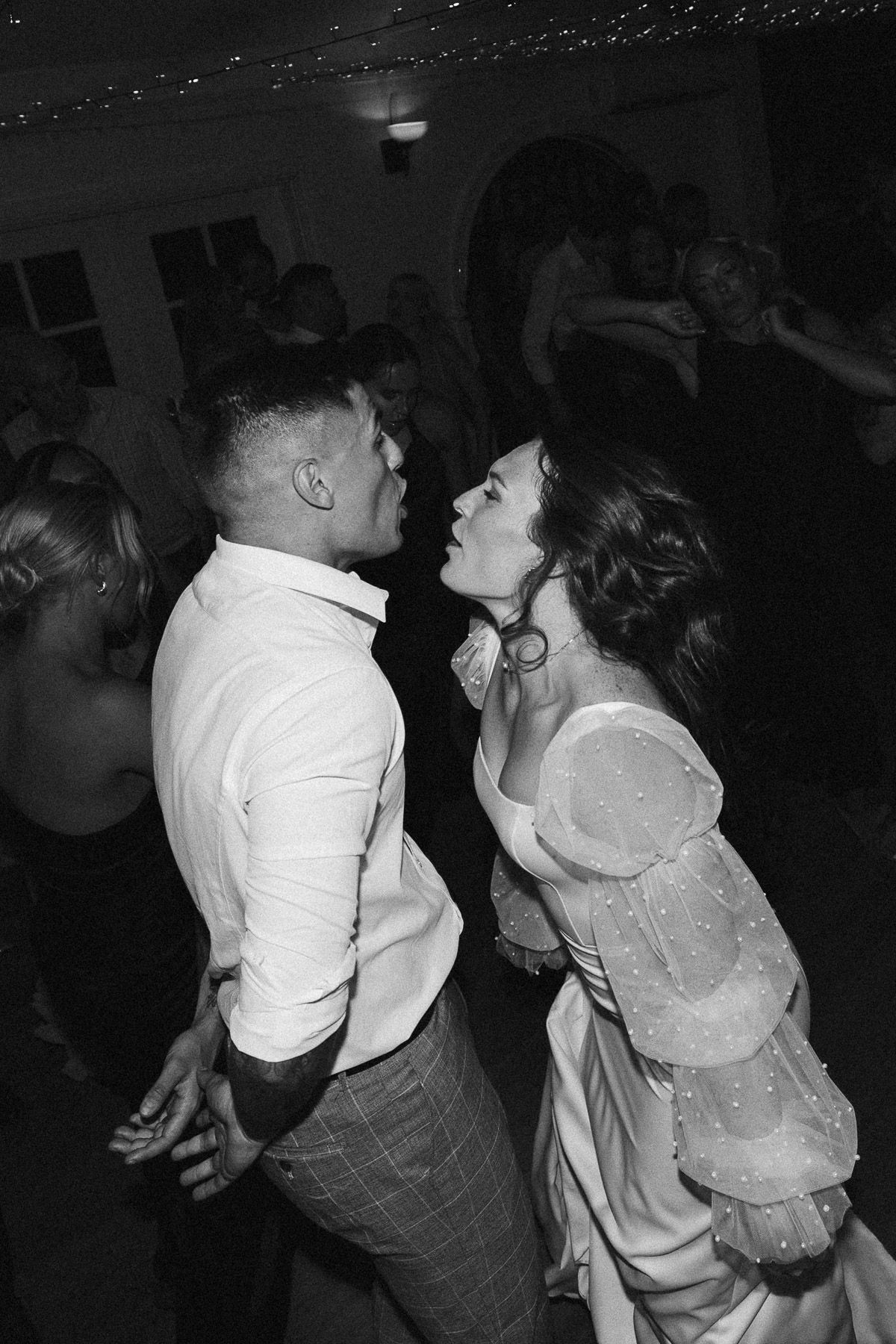 Couple dancing closely together at a wedding reception in black and white photography.