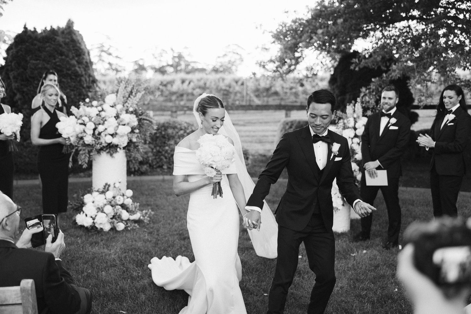 Black and white photo of joyful moment during outdoor wedding ceremony.