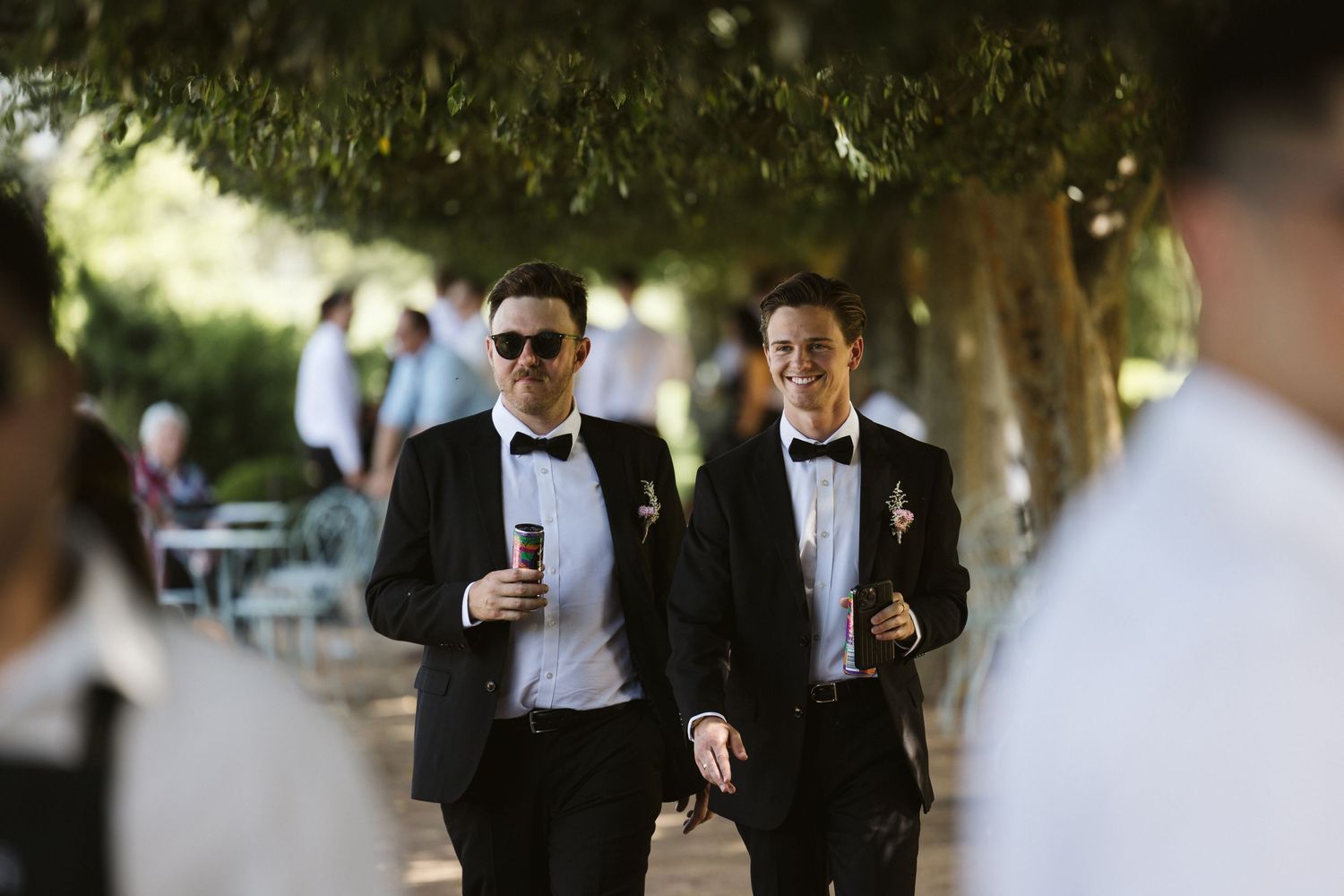Well-dressed guests walking through an outdoor garden party setting.