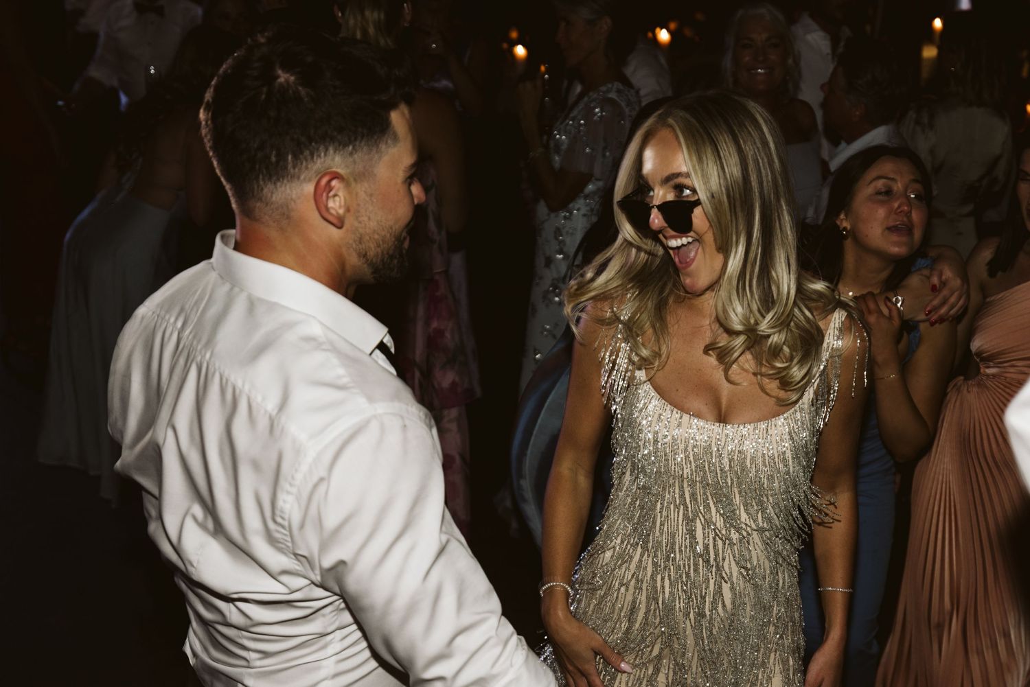 A couple sharing a joyful moment on the dance floor with a sparkly dress catching the light.