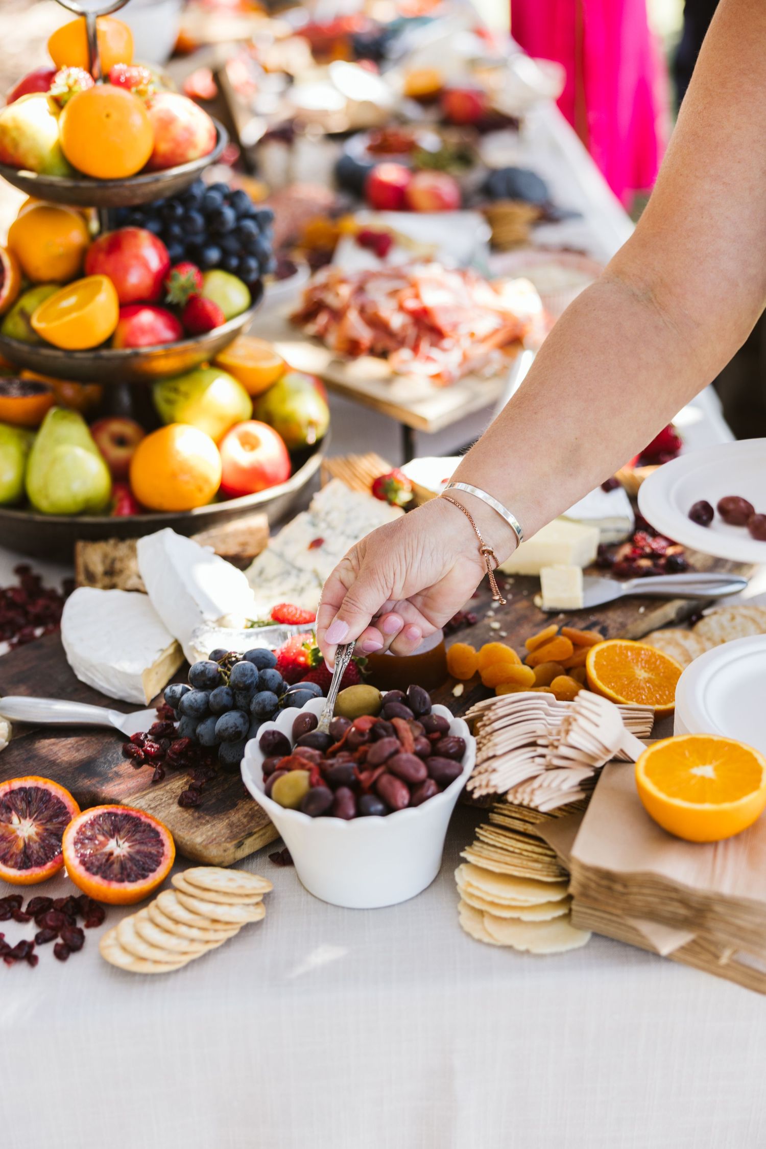 Beautifully arranged charcuterie board with fresh fruits, crackers, and appetizers at an outdoor event.
