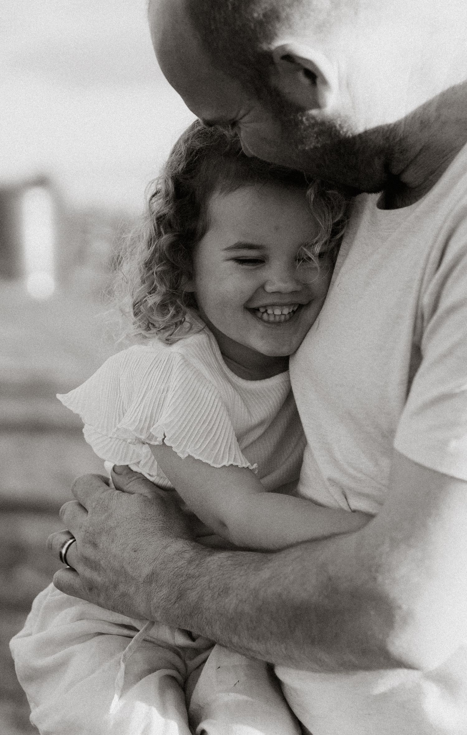 Black and white photo of a smiling young girl with curly hair. Katie Charlotte Photography