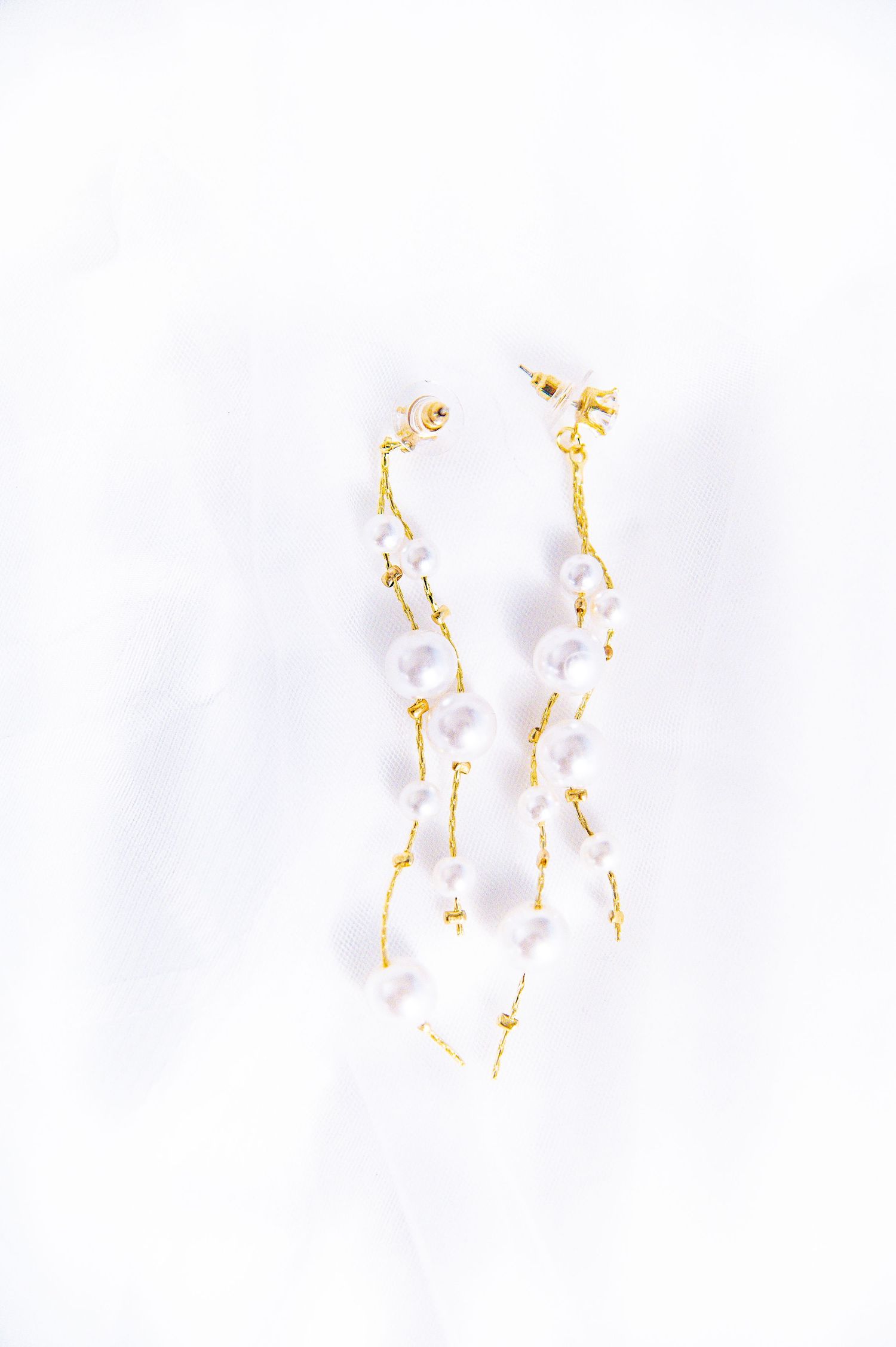 Elegant gold and pearl drop earrings photographed on white background.