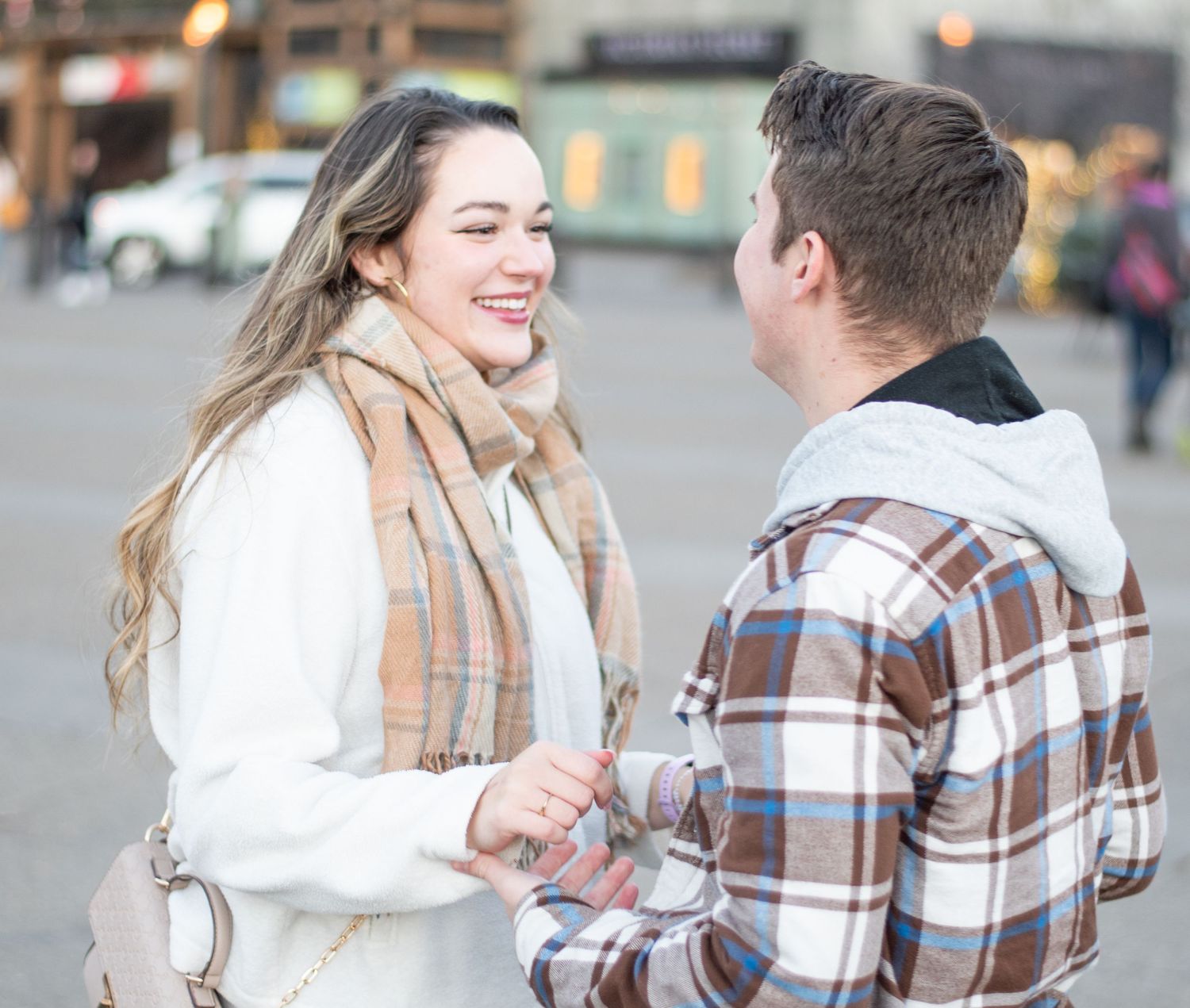 Couple in winter clothing embracing outdoors on a city street.