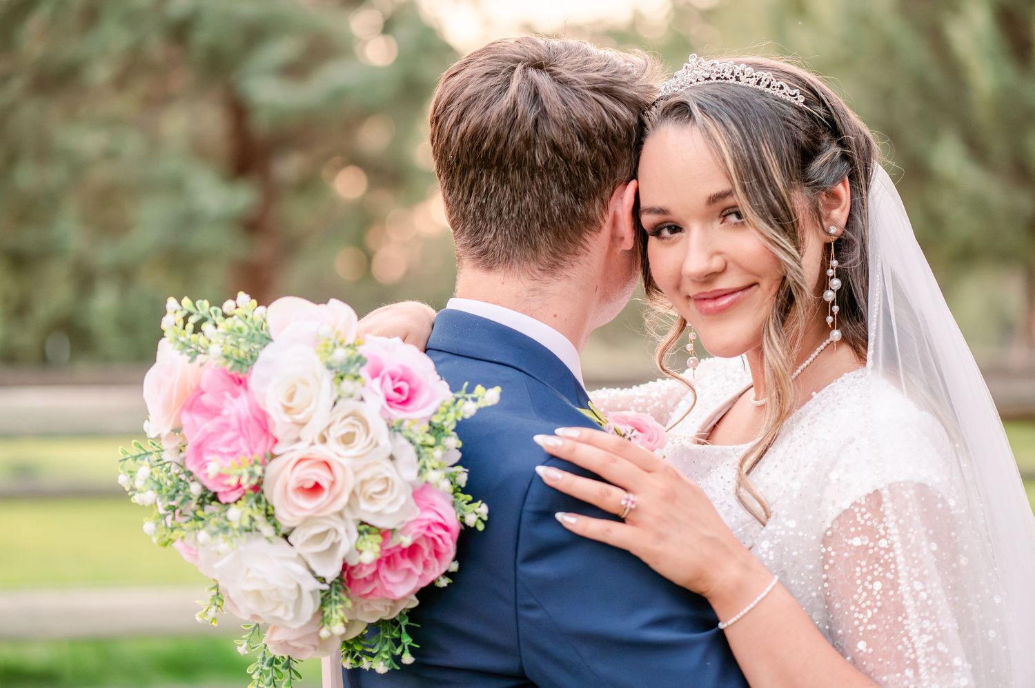 Bride and groom sharing tender moment in garden with pink flowers.