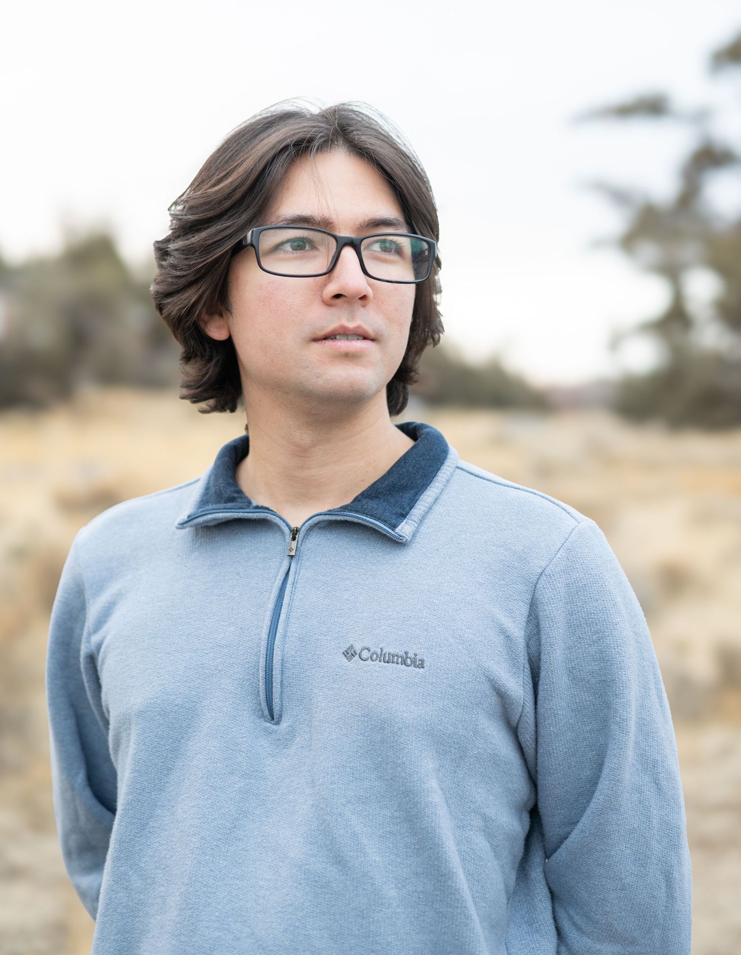 Person wearing a light blue Columbia fleece jacket and glasses stands in an outdoor setting.
