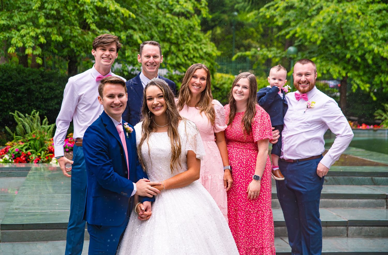 Wedding party group photos in garden setting with greenery and formal attire.
