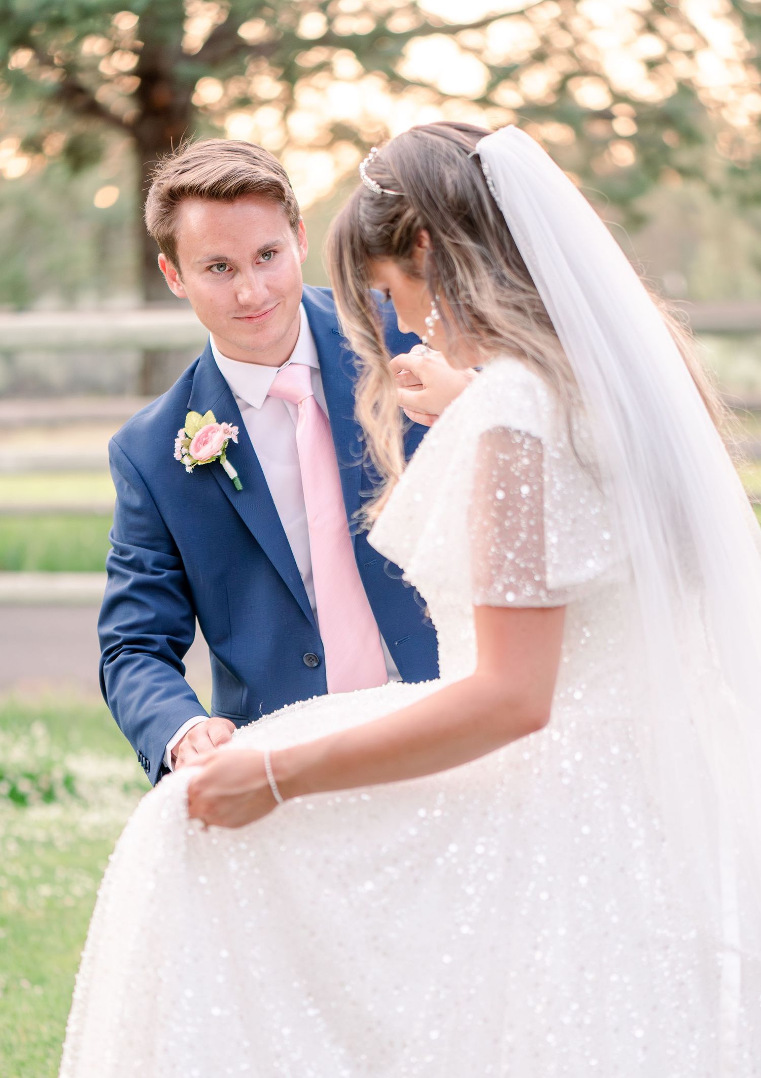 Elegant wedding couple shares tender moment in outdoor garden setting with soft lighting.