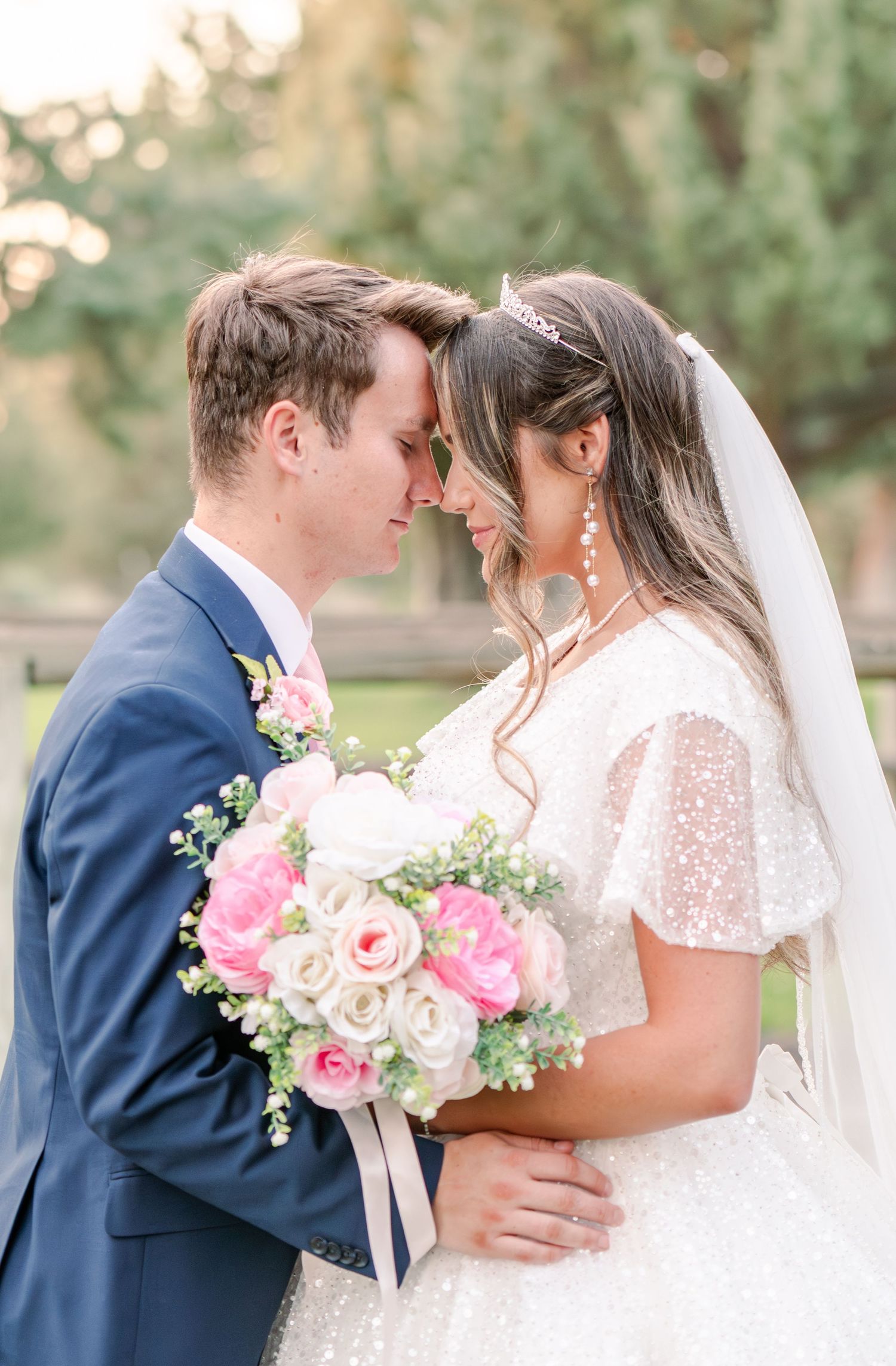 Romantic garden wedding portraits with bride in lace dress holding pink rose bouquet.