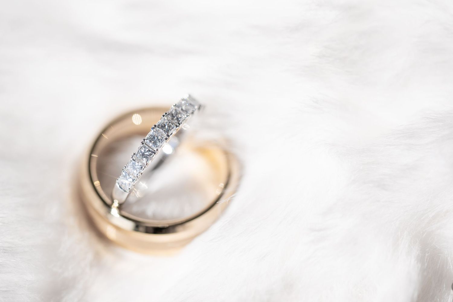 Close-up of diamond engagement rings and wedding bands on a white marble surface.