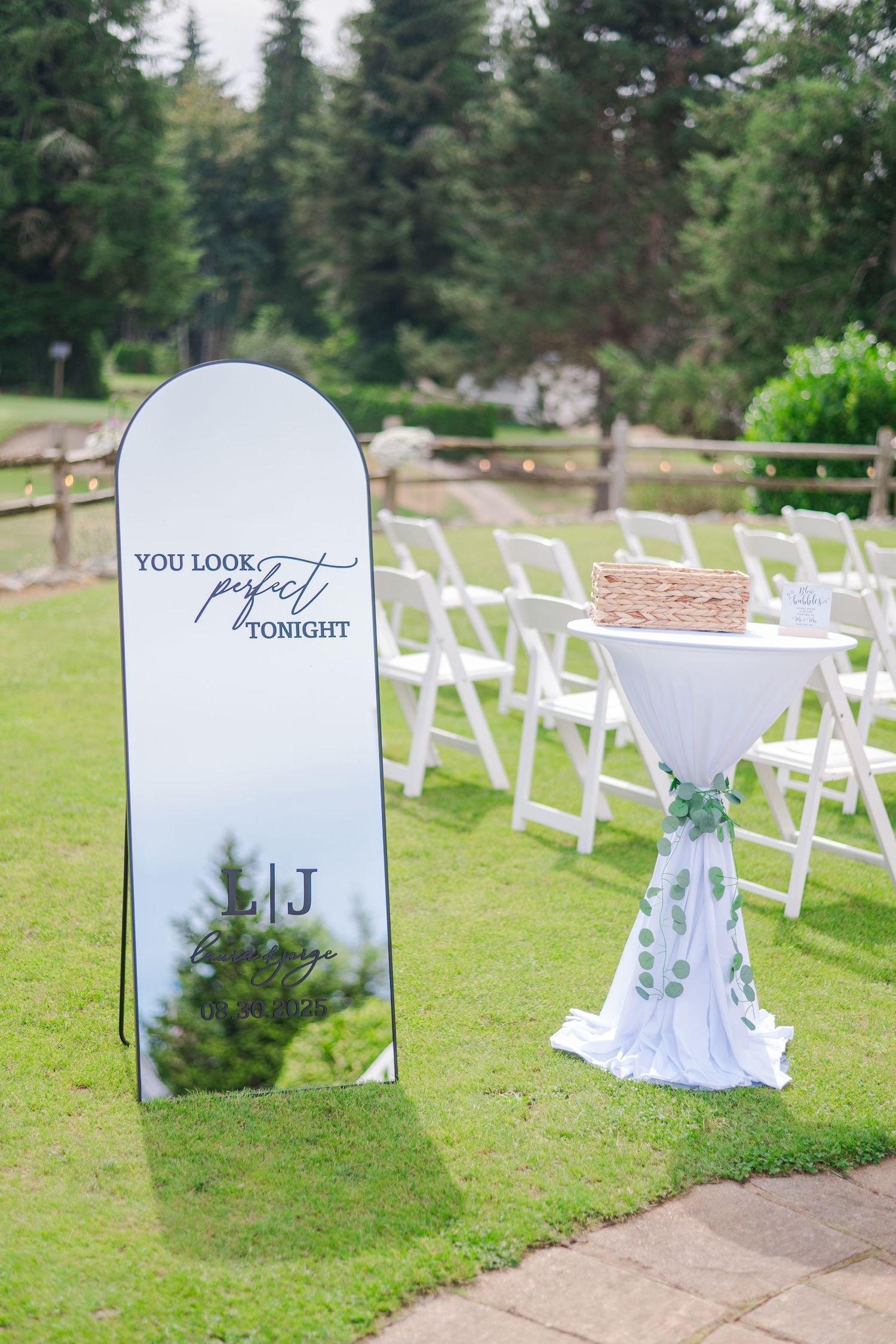 Elegant outdoor wedding setup with a decorative mirror sign reading You Look Perfect Tonight on green lawn.