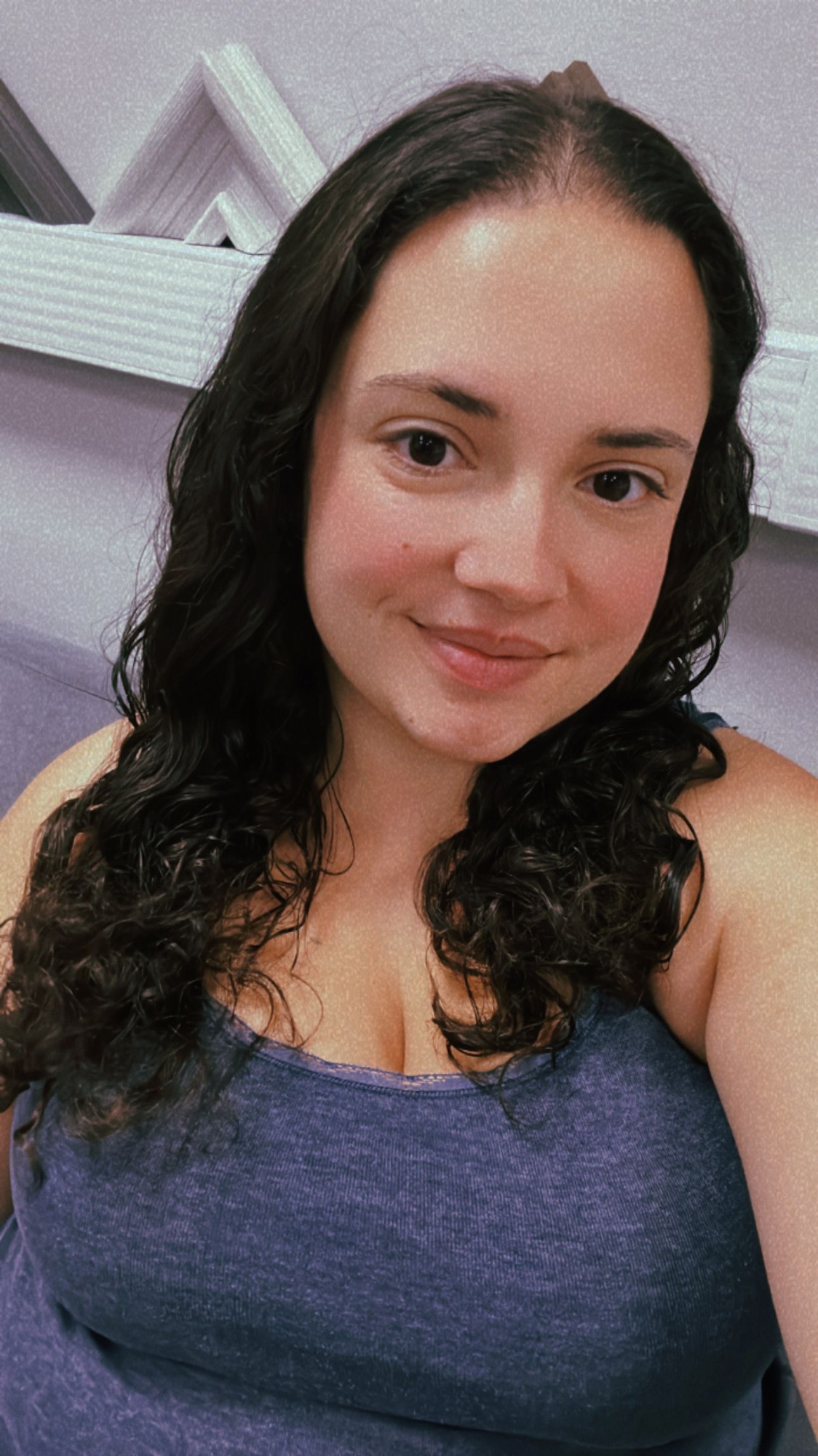 A selfie showing a woman with dark curly hair wearing a purple top.