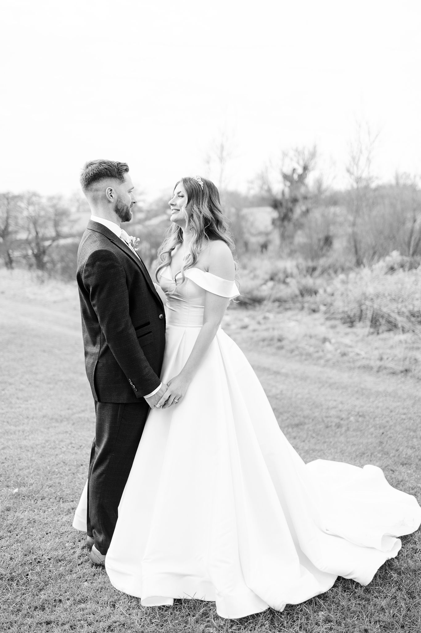 A black and white portrait of newlyweds sharing an intimate moment outdoors.