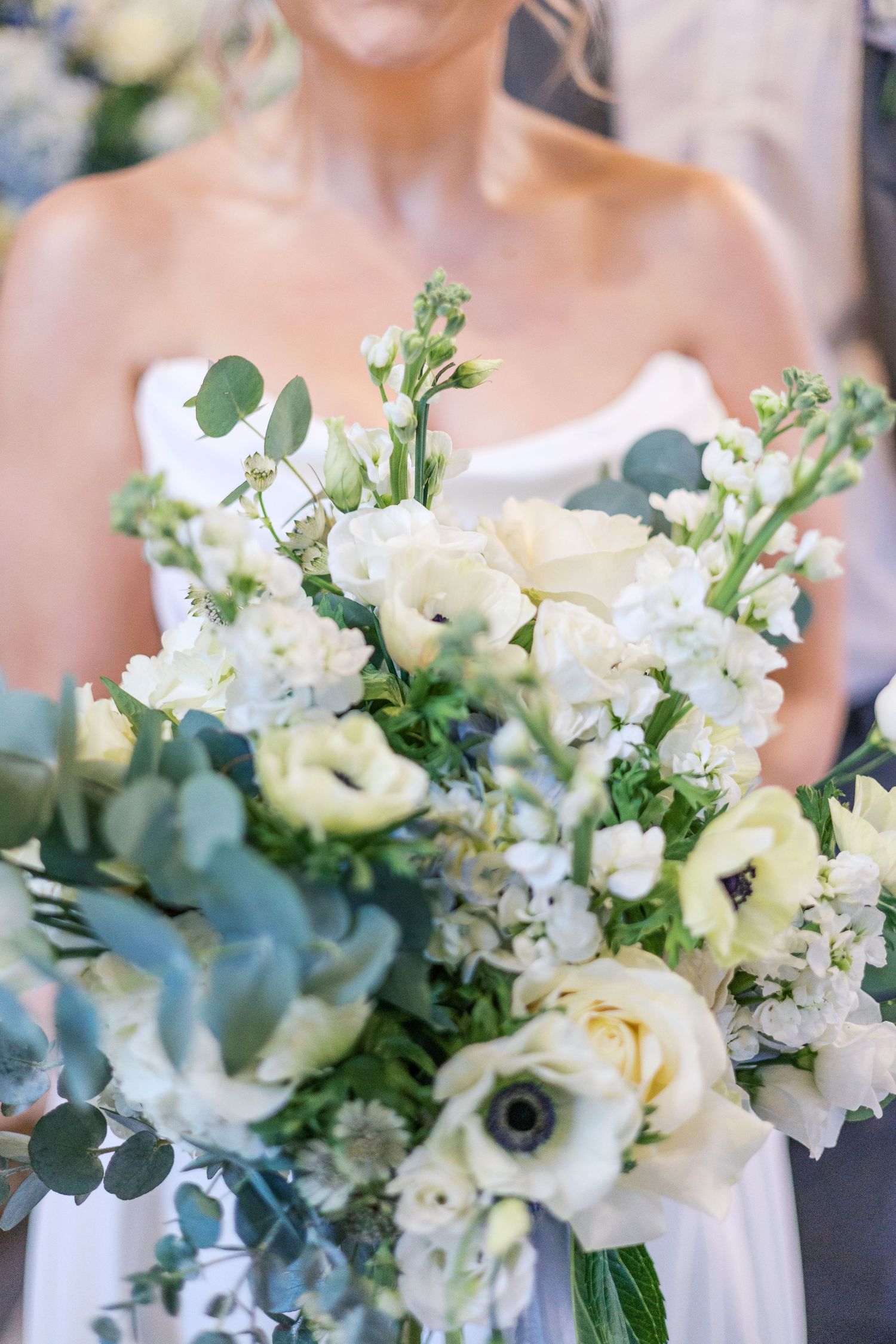 Elegant white and green bridal bouquet with roses, eucalyptus leaves, and delicate wildflowers.