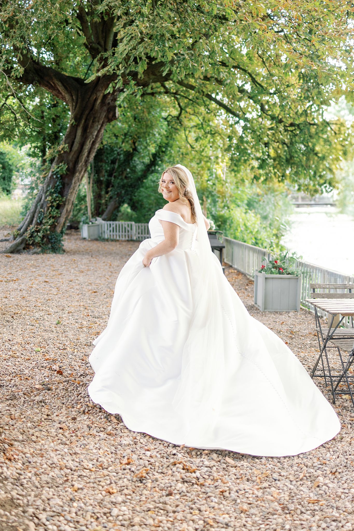 A white wedding gown spins elegantly against a backdrop of autumn foliage and scattered leaves on the ground.