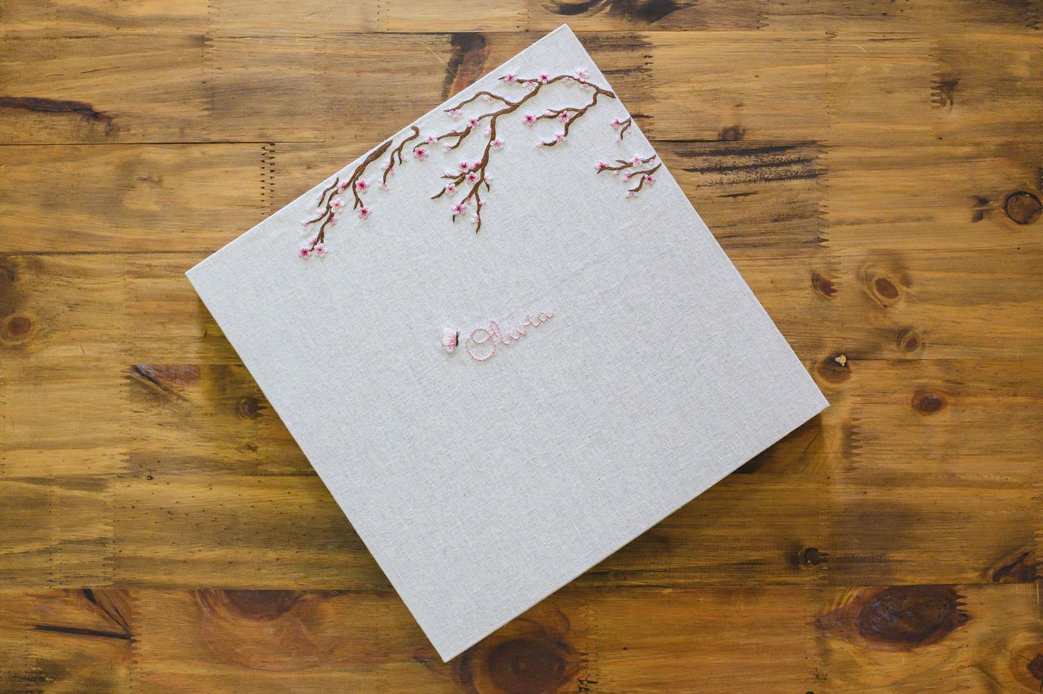 Cherry blossom branches delicately painted on white paper against a rustic wooden surface.