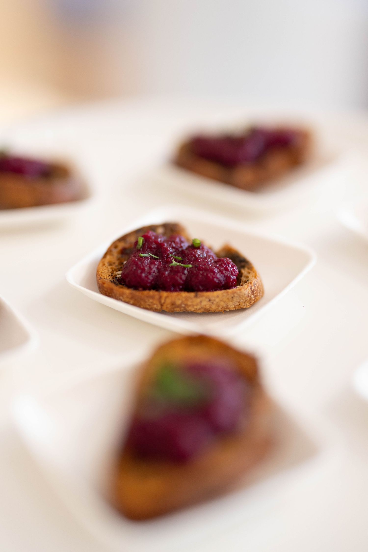 Artfully plated appetizers with purple garnish on white plates.