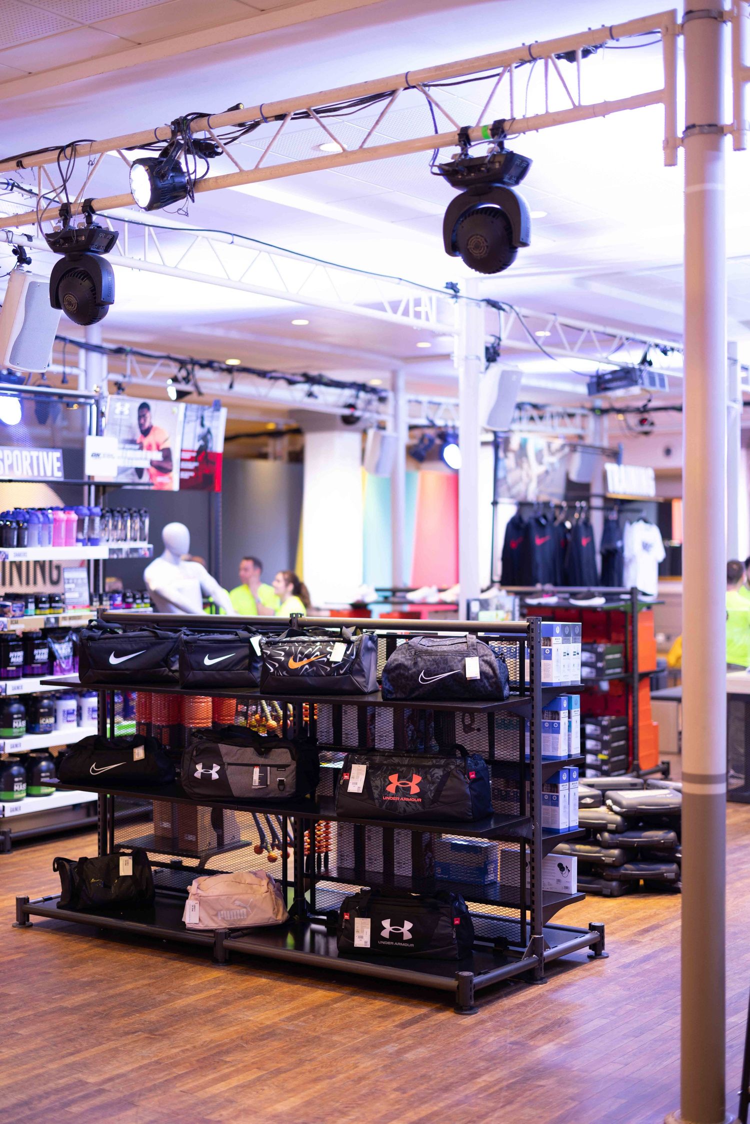 Spacious retail floor with wooden flooring and merchandise displays under track lighting.
