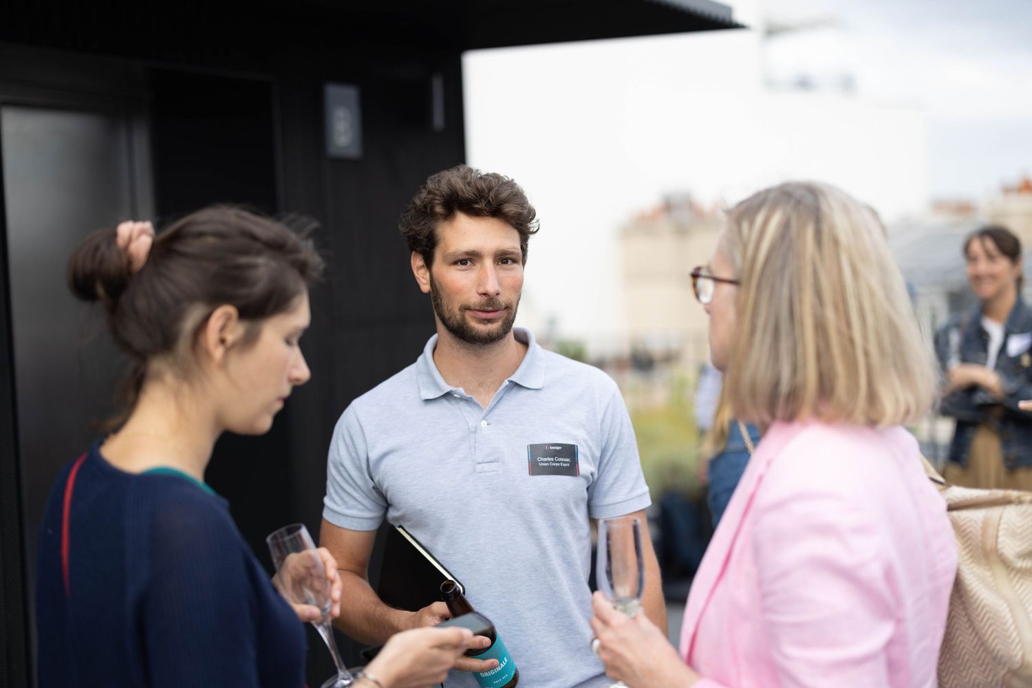 Three people engaged in casual conversation at an outdoor event.