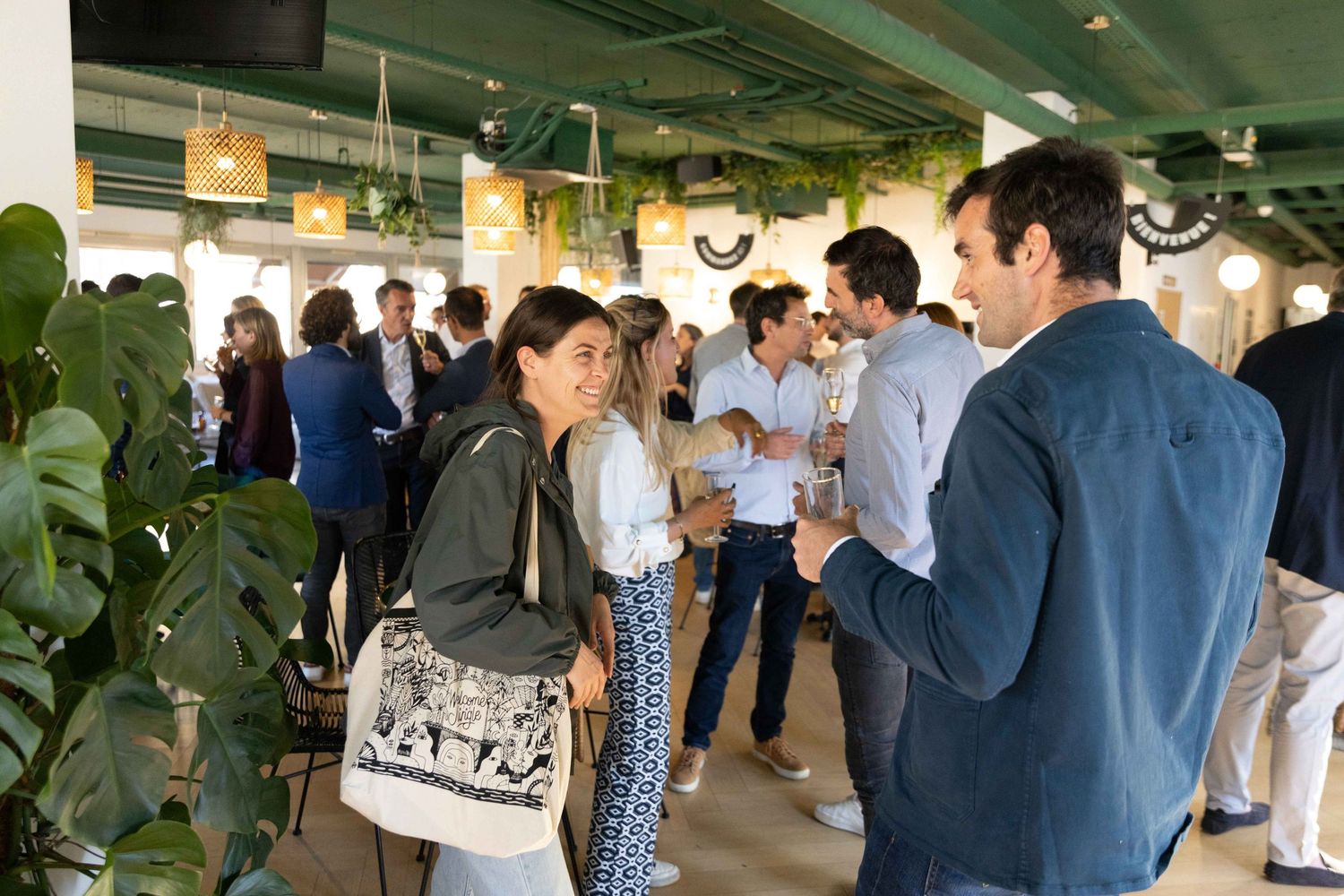 Business professionals networking in a modern office space with plants and natural lighting.