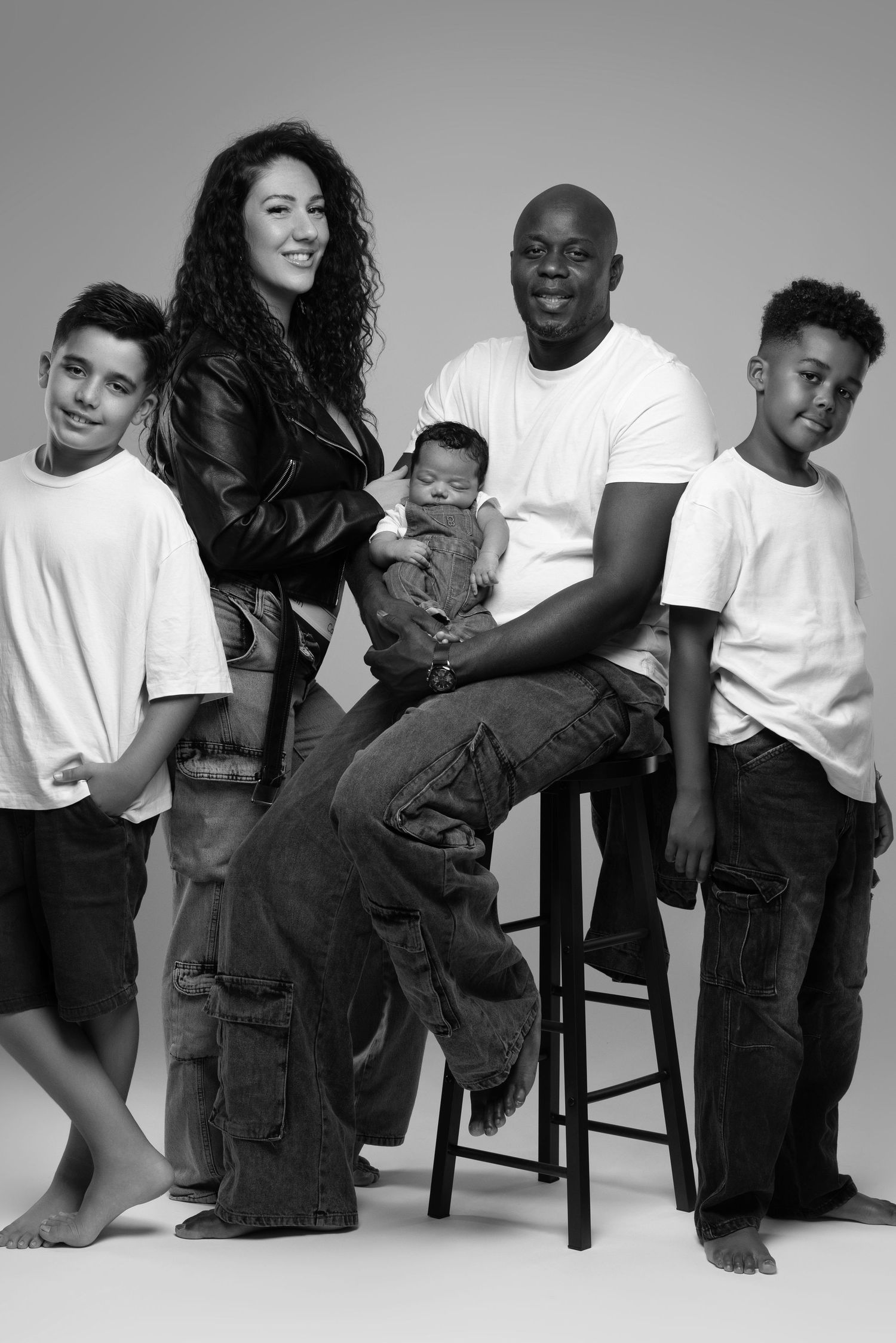 Black and white fashion photo series showing models in white t-shirts and dark pants posing casually against light backdrop.