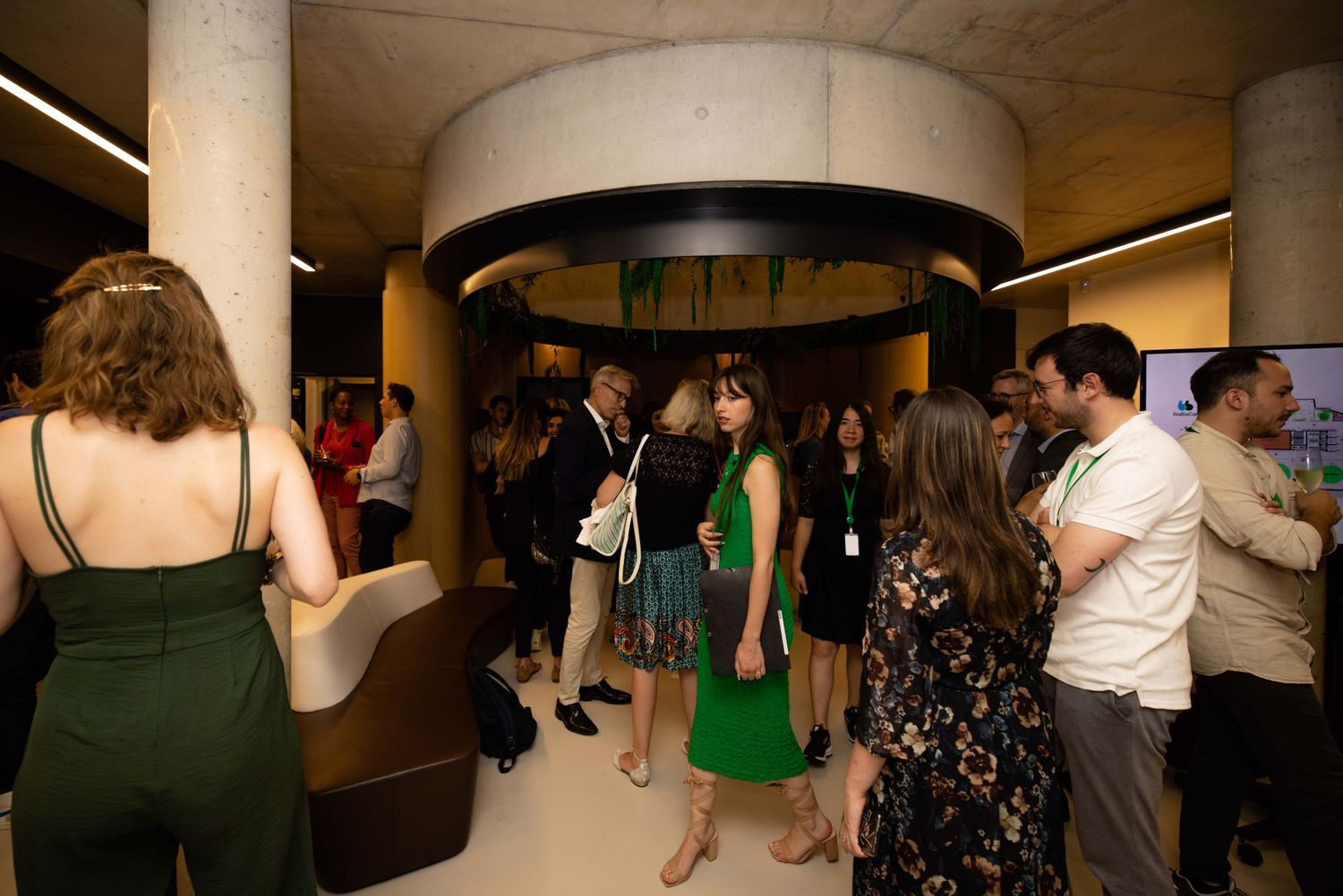 Conference attendees gather in a modern auditorium space for a presentation.