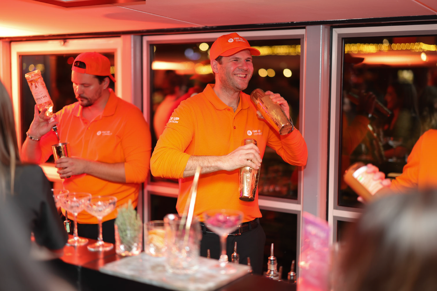 Staff members in bright orange uniforms working behind a bar counter.