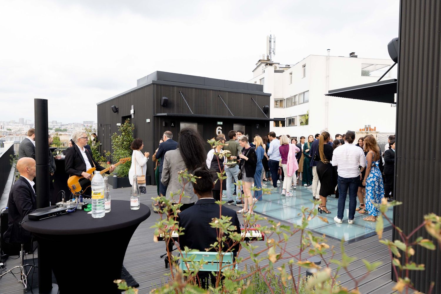 Outdoor event setup with black columns and scattered groups of attendees mingling.